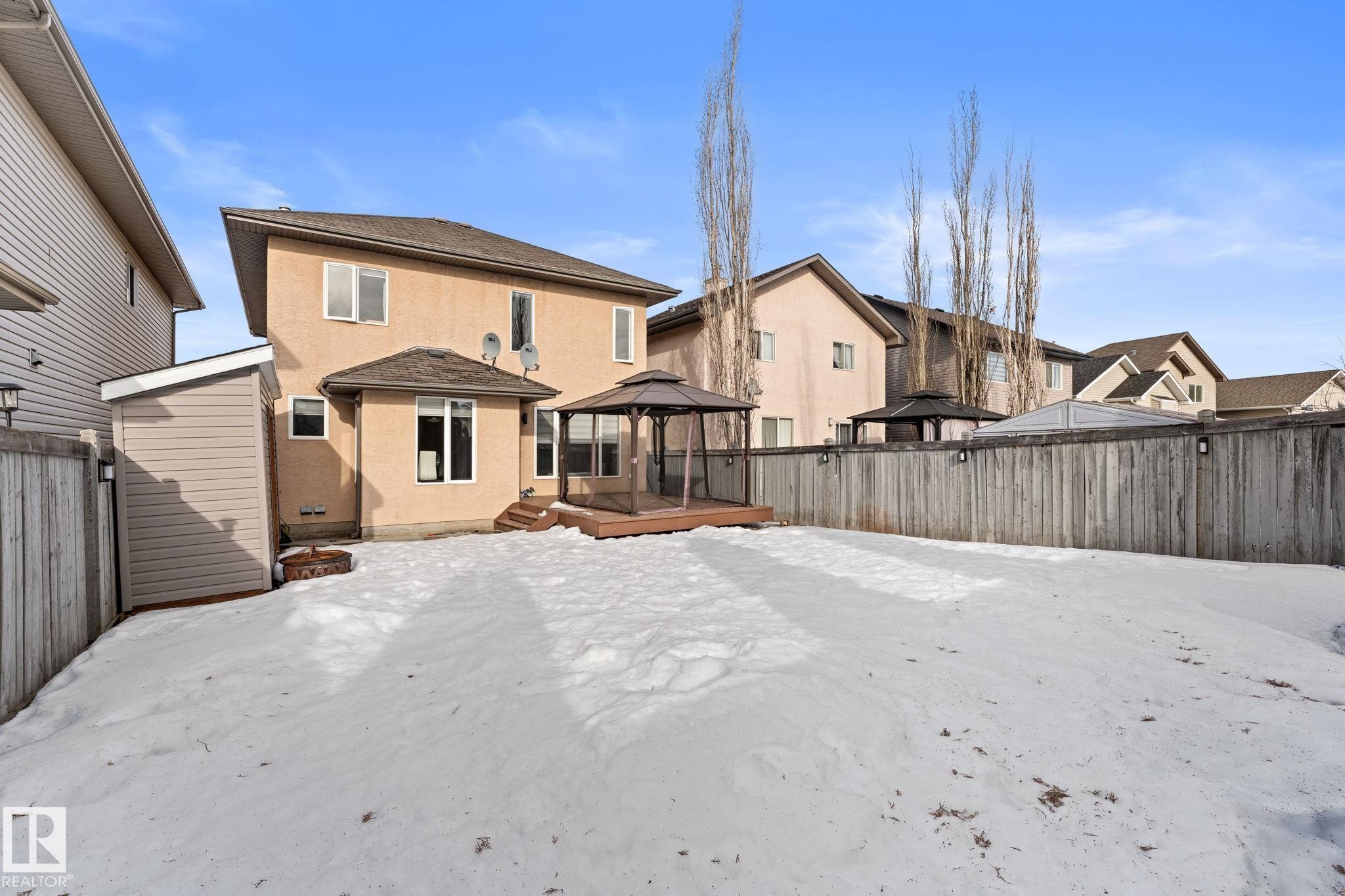 Snow covered house featuring a gazebo, a fenced backyard, a wooden deck, and stucco siding - 10655 181 Avenue, Edmonton, AB - Outdoor With Exterior