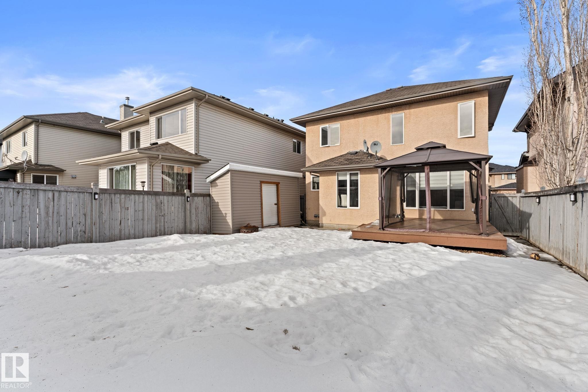 Snow covered house featuring a gazebo, a fenced backyard, stucco siding, a deck, and a storage shed - 10655 181 Avenue, Edmonton, AB - Outdoor