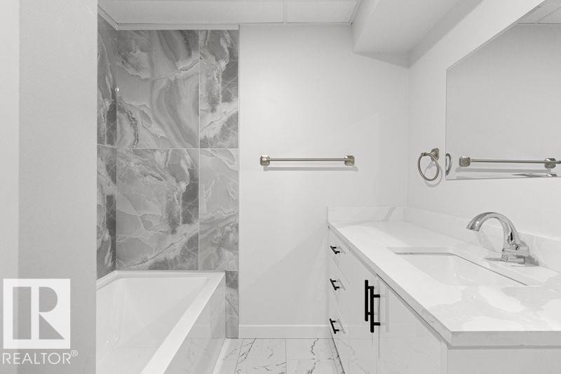 Bathroom featuring vanity, a tub with marble appearance, and light marble finish flooring - 875 Juniper Avenue, Sherwood Park, AB - Indoor Photo Showing Bathroom