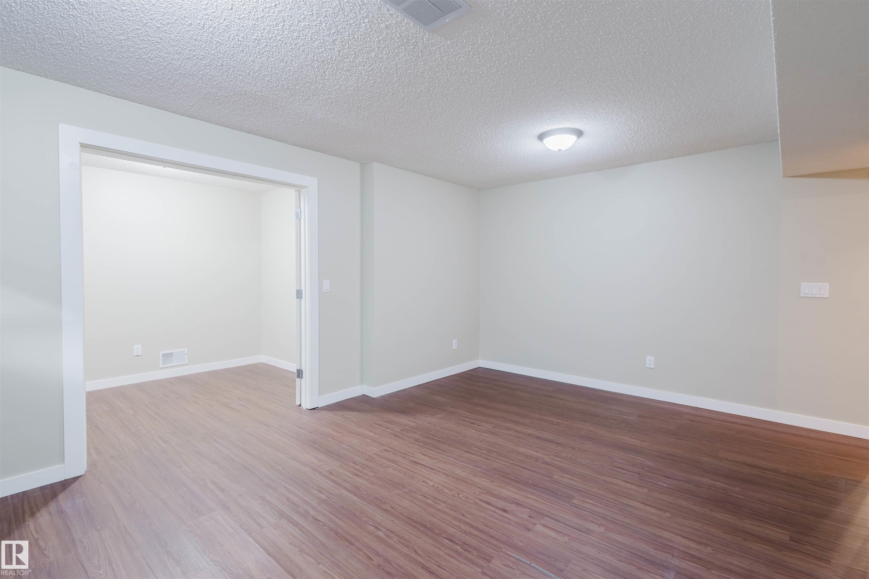 Unfurnished room with a textured ceiling and wood finished floors - 3534 Mclean Crescent, Edmonton, AB - Indoor Photo Showing Other Room