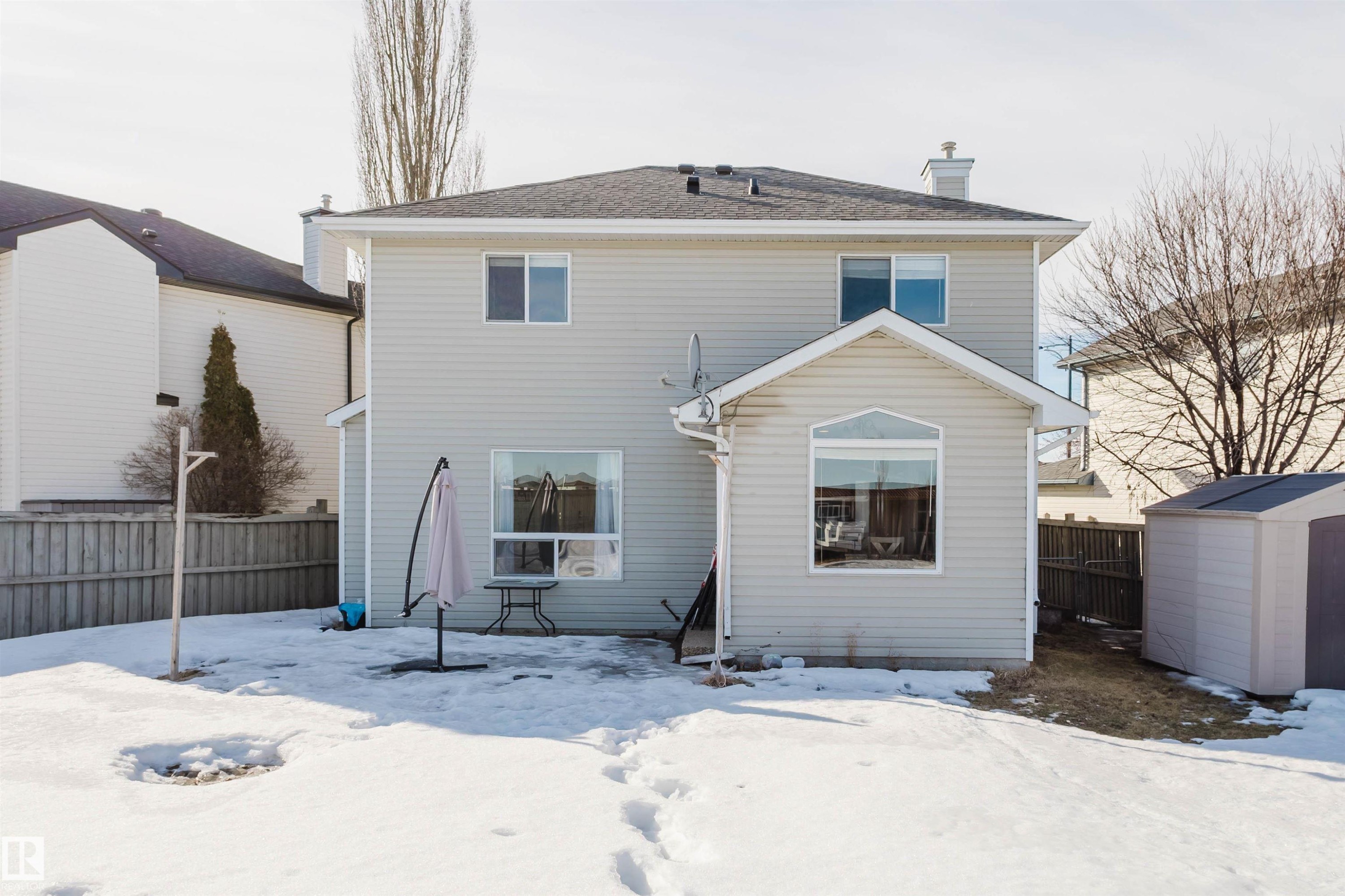 Snow covered house with a storage shed, a fenced backyard, a chimney, and a patio area - 3534 Mclean Crescent, Edmonton, AB - Outdoor With Exterior