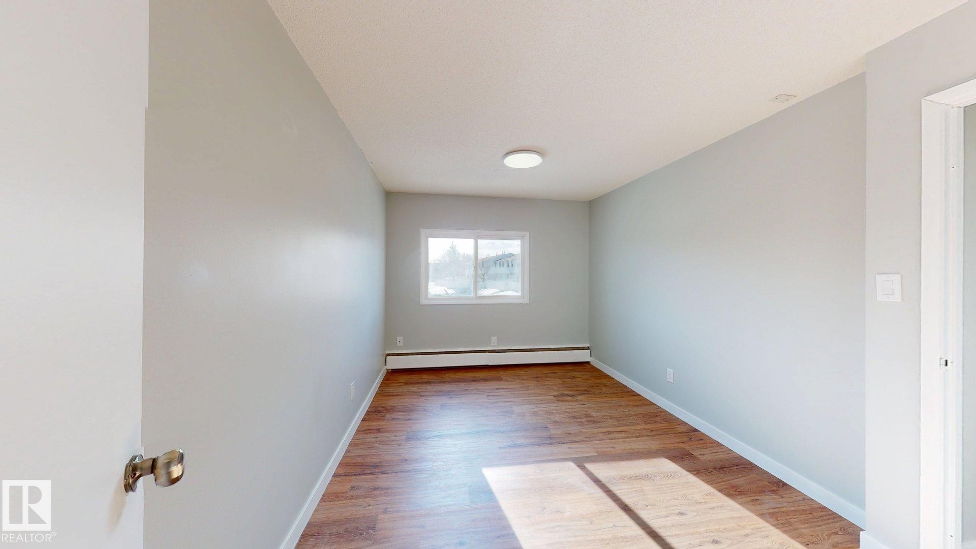 Empty room with light wood-style flooring and baseboard heating - 611 2908 116A Avenue, Edmonton, AB - Indoor Photo Showing Other Room