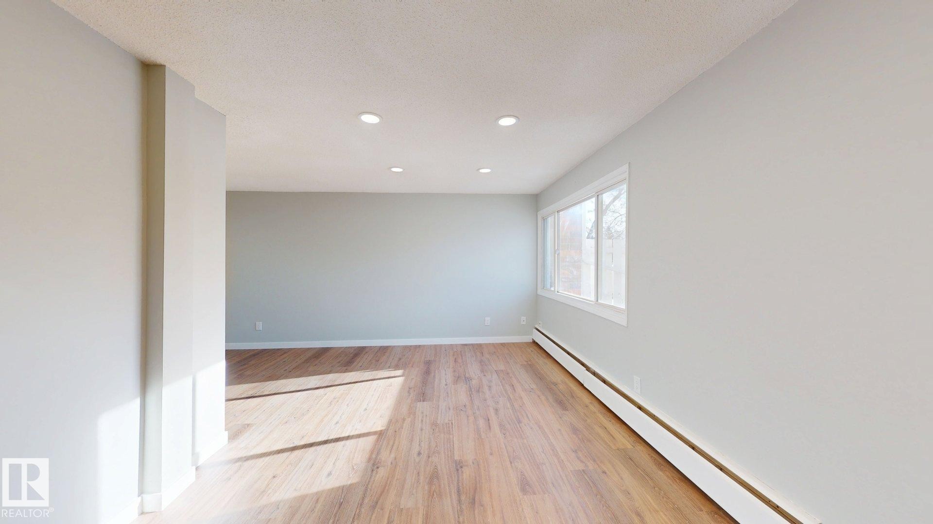 Empty room with a baseboard radiator, light wood finished floors, recessed lighting, and a textured ceiling - 611 2908 116A Avenue, Edmonton, AB - Indoor Photo Showing Other Room