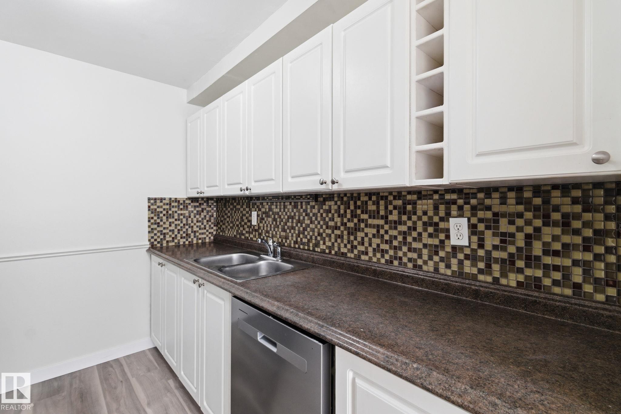 Kitchen with dishwasher, white cabinetry, dark countertops, and light wood finished floors - 180 Londonderry Square, Edmonton, AB - Indoor Photo Showing Kitchen With Double Sink