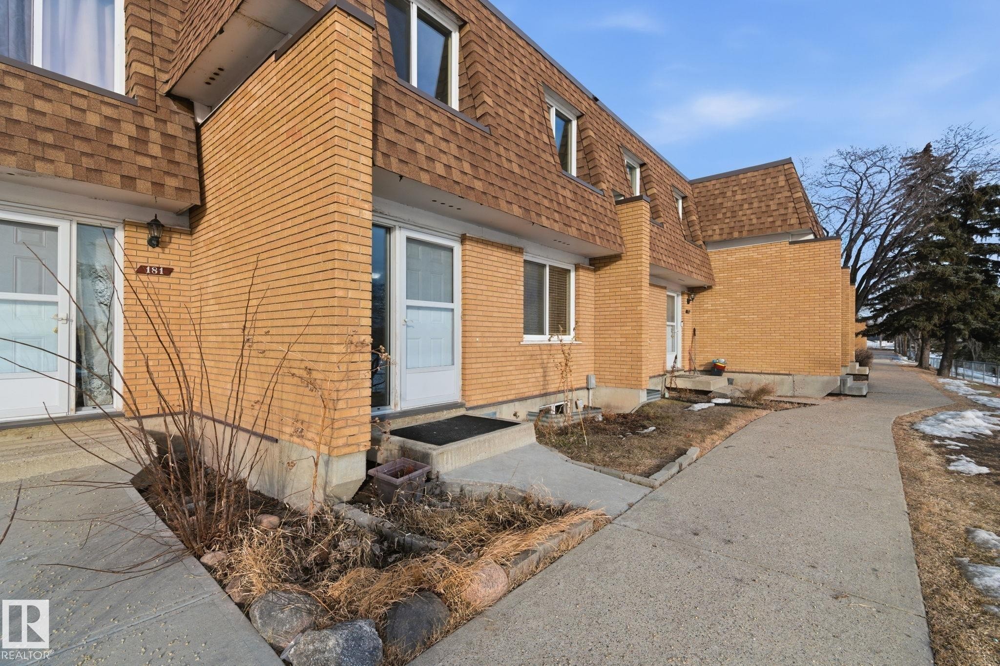 Property entrance with a shingled roof, mansard roof, and brick siding - 180 Londonderry Square, Edmonton, AB - Outdoor With Exterior