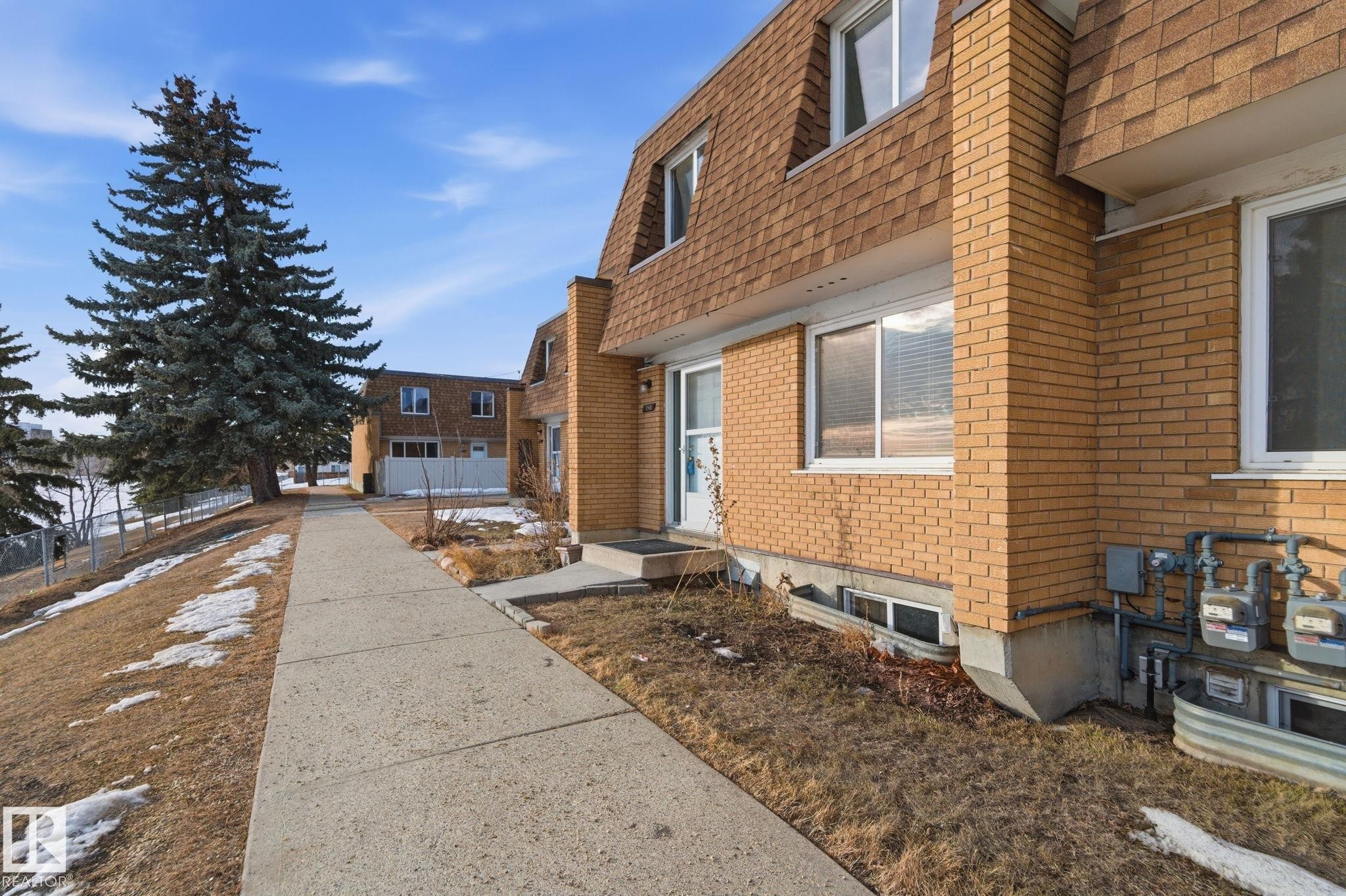 View of front of home featuring brick siding, mansard roof, and a shingled roof - 180 Londonderry Square, Edmonton, AB - Outdoor