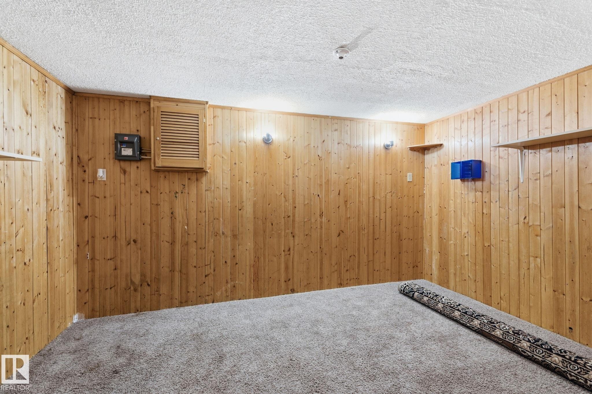 Unfurnished room featuring carpet floors, a textured ceiling, and wooden walls - 180 Londonderry Square, Edmonton, AB - Indoor