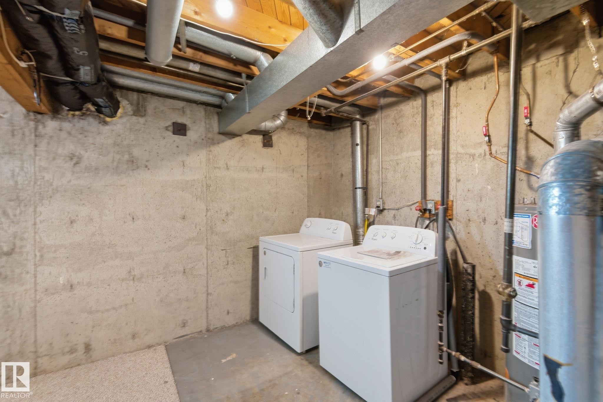 Laundry area with unfinished concrete floors, washing machine and clothes dryer, and gas water heater - 180 Londonderry Square, Edmonton, AB - Indoor