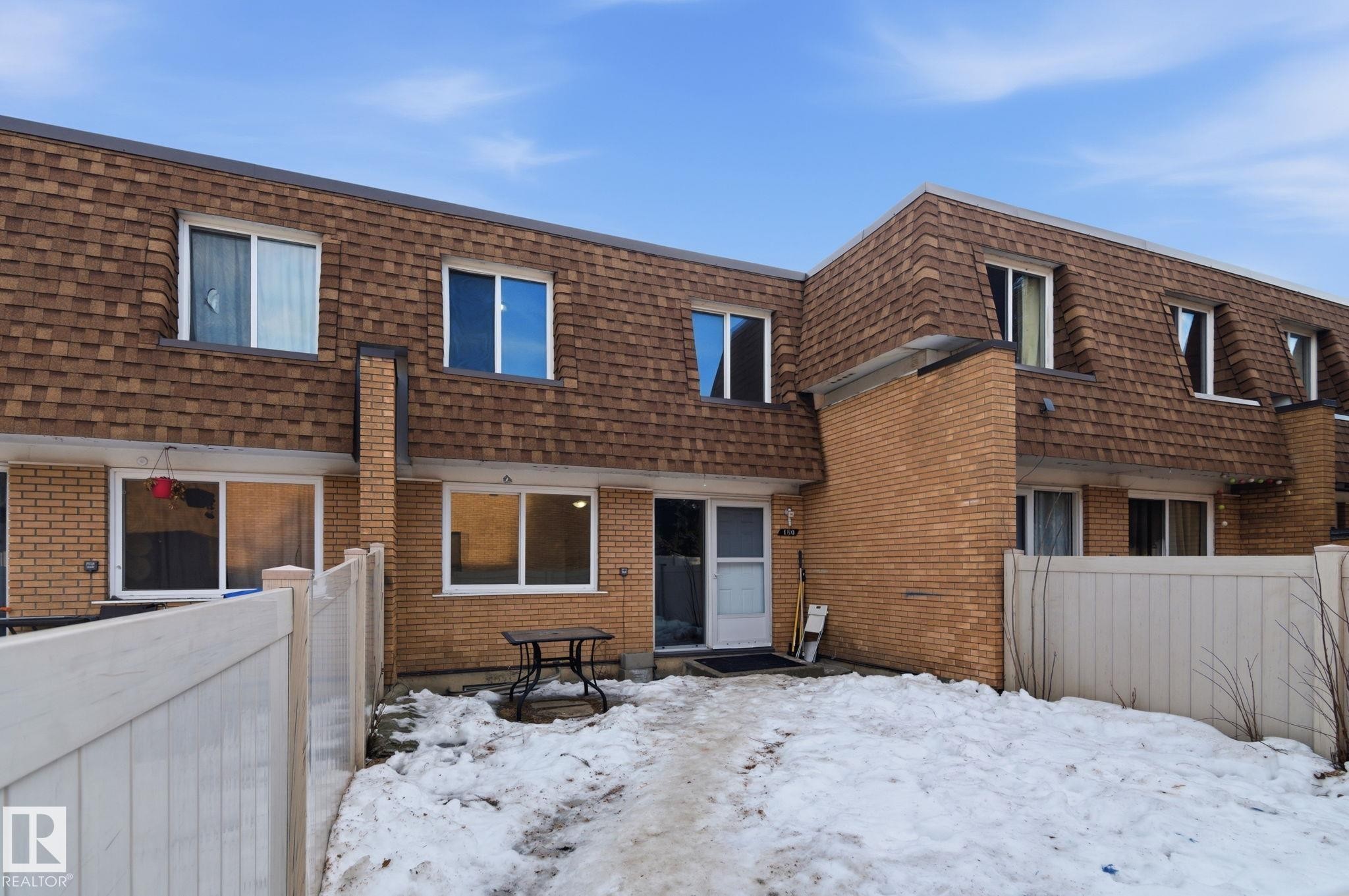 Snow covered back of property featuring mansard roof, brick siding, and roof with shingles - 180 Londonderry Square, Edmonton, AB - Outdoor With Exterior