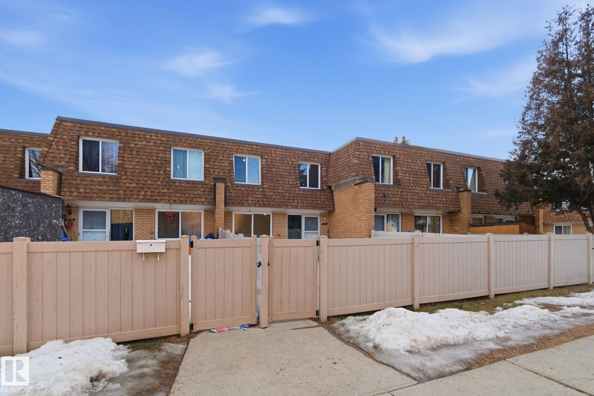 Rear view of property with mansard roof, a gate, and brick siding - 180 Londonderry Square, Edmonton, AB - Outdoor