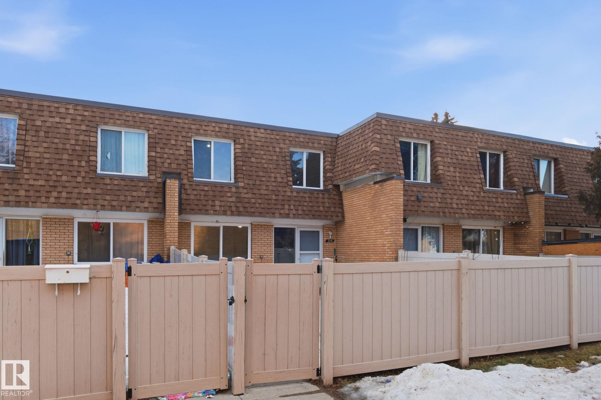 Back of property featuring mansard roof, a gate, and brick siding - 180 Londonderry Square, Edmonton, AB - Outdoor With Exterior