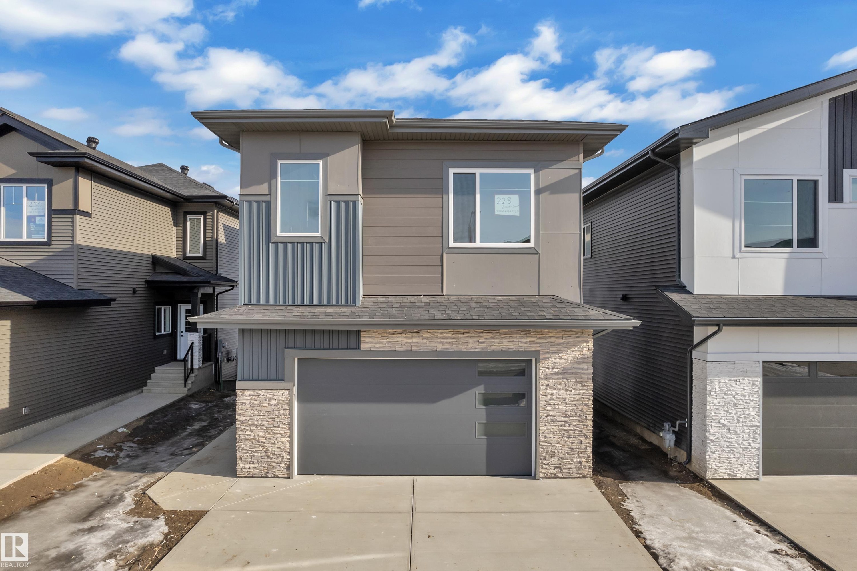 Contemporary house with stone siding, an attached garage, concrete driveway, and board and batten siding - 228 Linden Loop, Leduc, AB - Outdoor With Facade