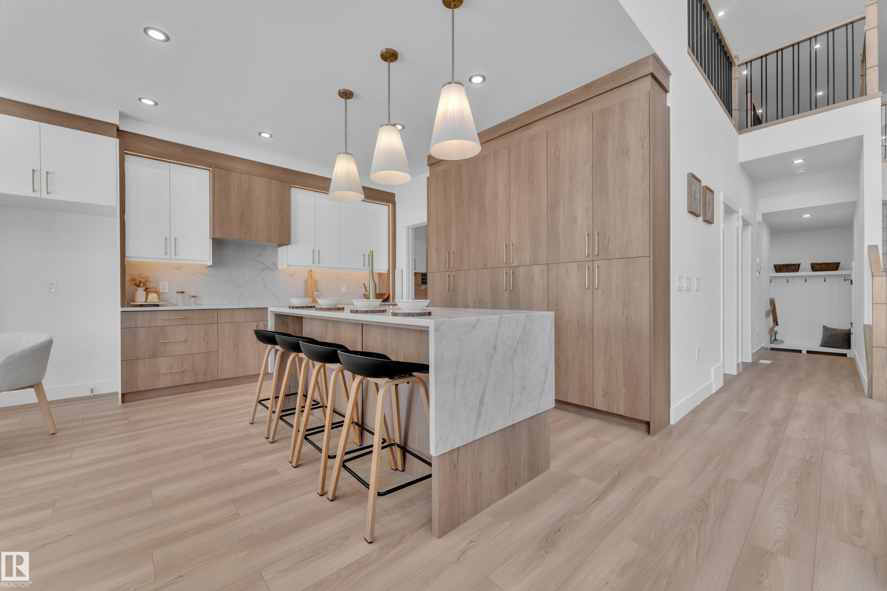 Kitchen featuring a center island with sink, a breakfast bar area, pendant lighting, light wood finished floors, and modern cabinets - 228 Linden Loop, Leduc, AB - Indoor