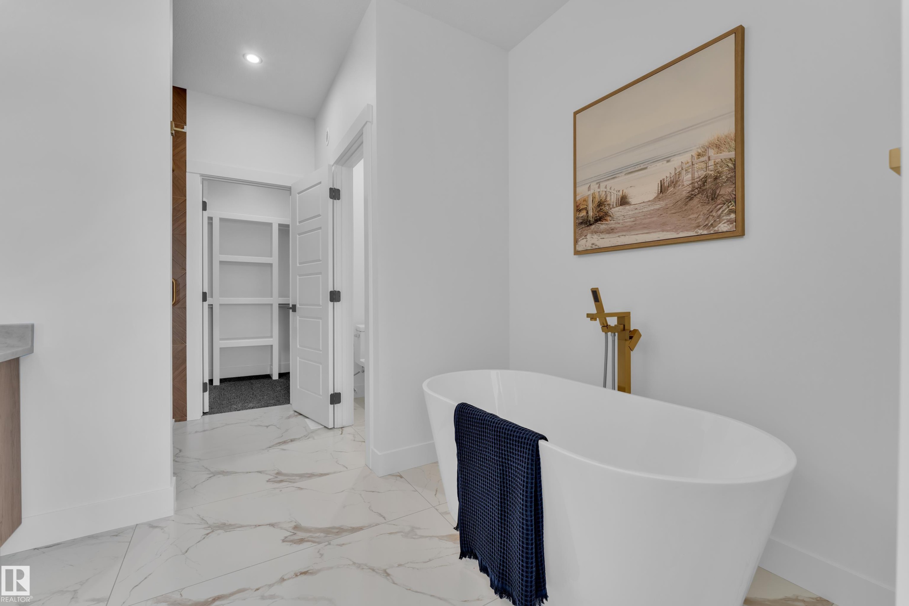 Bathroom with a spacious closet, vanity, recessed lighting, a freestanding tub, and light marble finish floors - 228 Linden Loop, Leduc, AB - Indoor