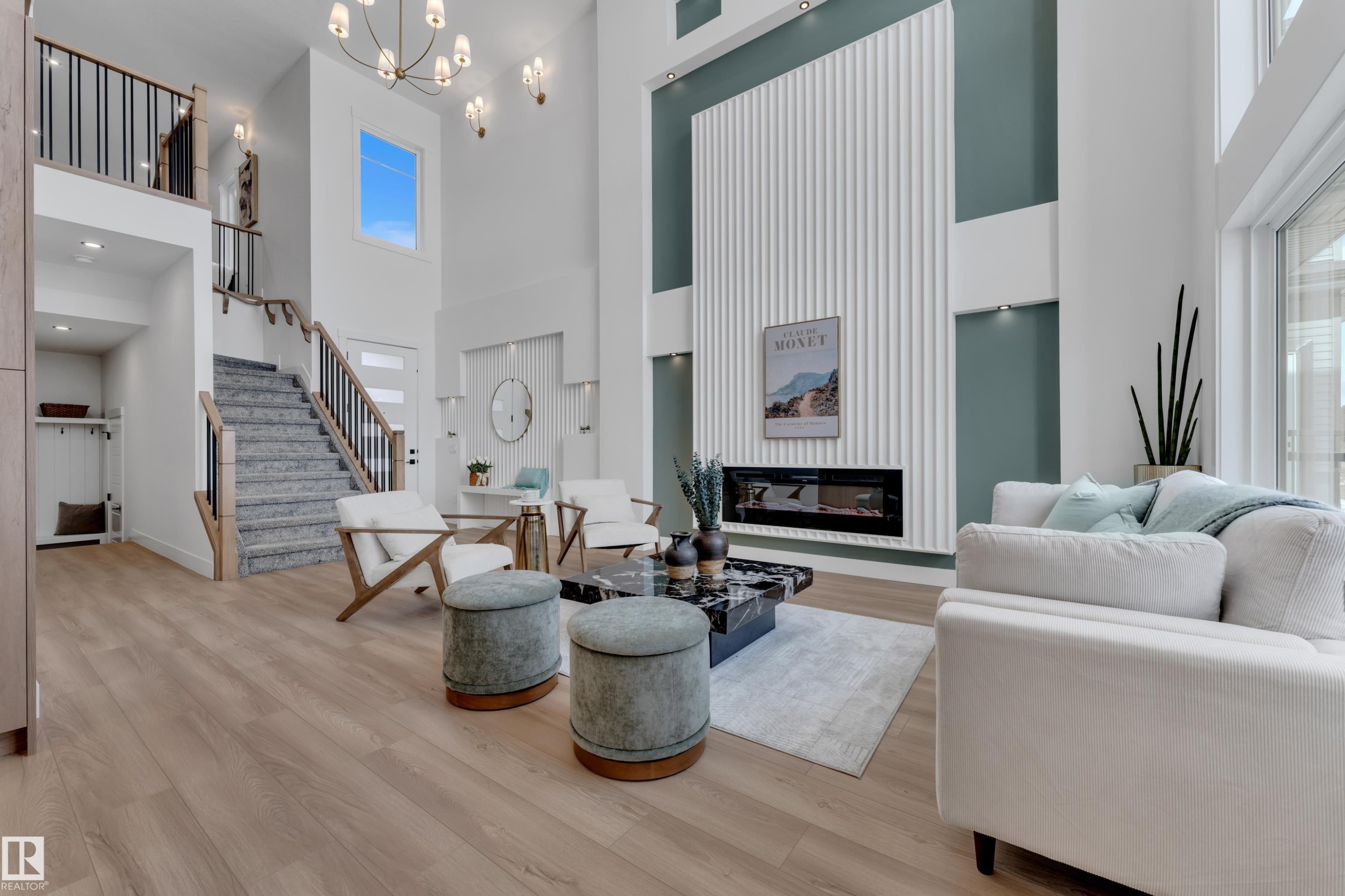 Living room featuring light wood-style floors, a high ceiling, a glass covered fireplace, and a chandelier - 228 Linden Loop, Leduc, AB - Indoor Photo Showing Living Room With Fireplace