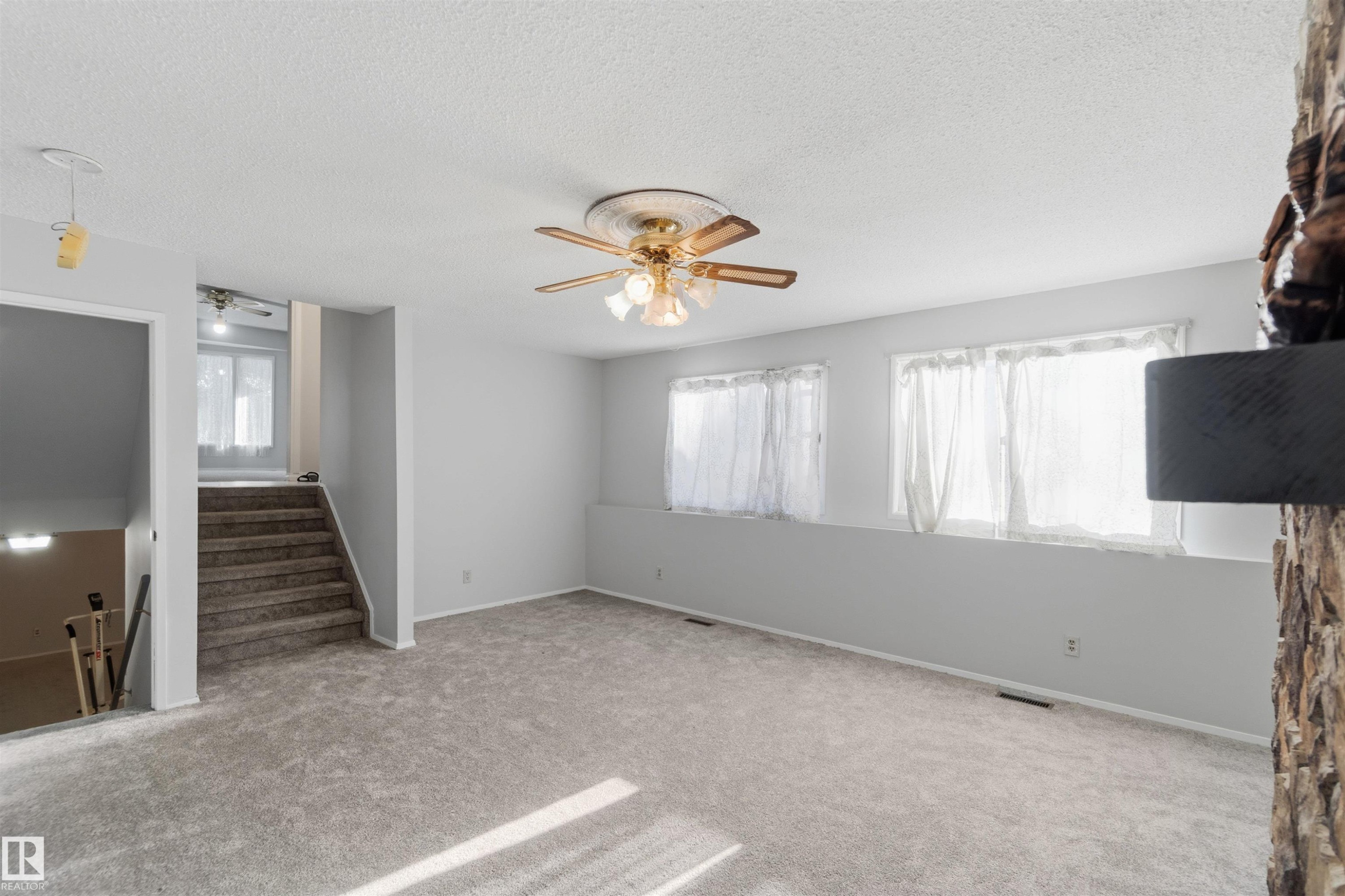 Unfurnished living room with a ceiling fan, carpet flooring, and a textured ceiling - 135 Humberstone Road, Edmonton, AB - Indoor Photo Showing Other Room