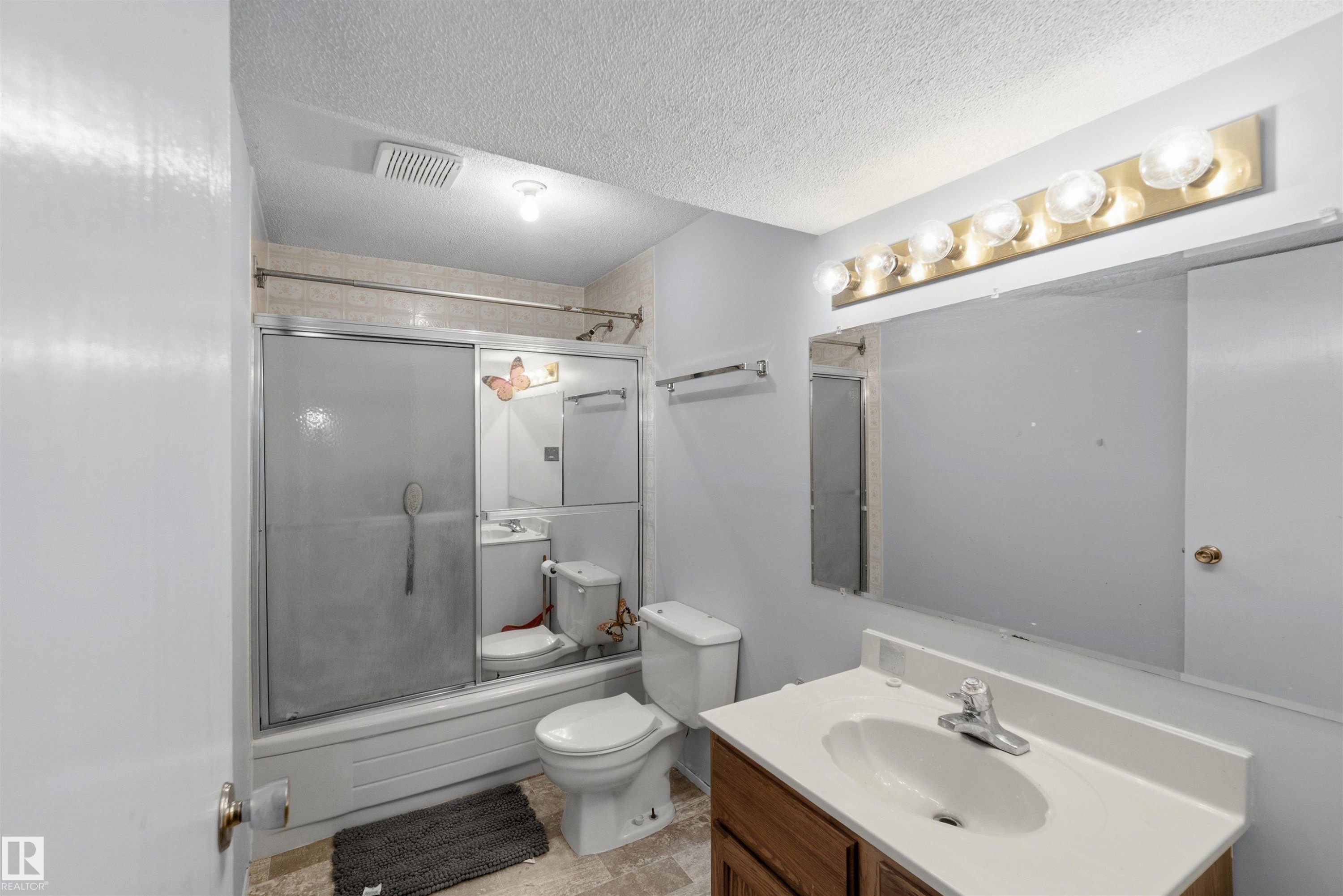 Bathroom with shower / bath combination with glass door, vanity, and a textured ceiling - 135 Humberstone Road, Edmonton, AB - Indoor Photo Showing Bathroom