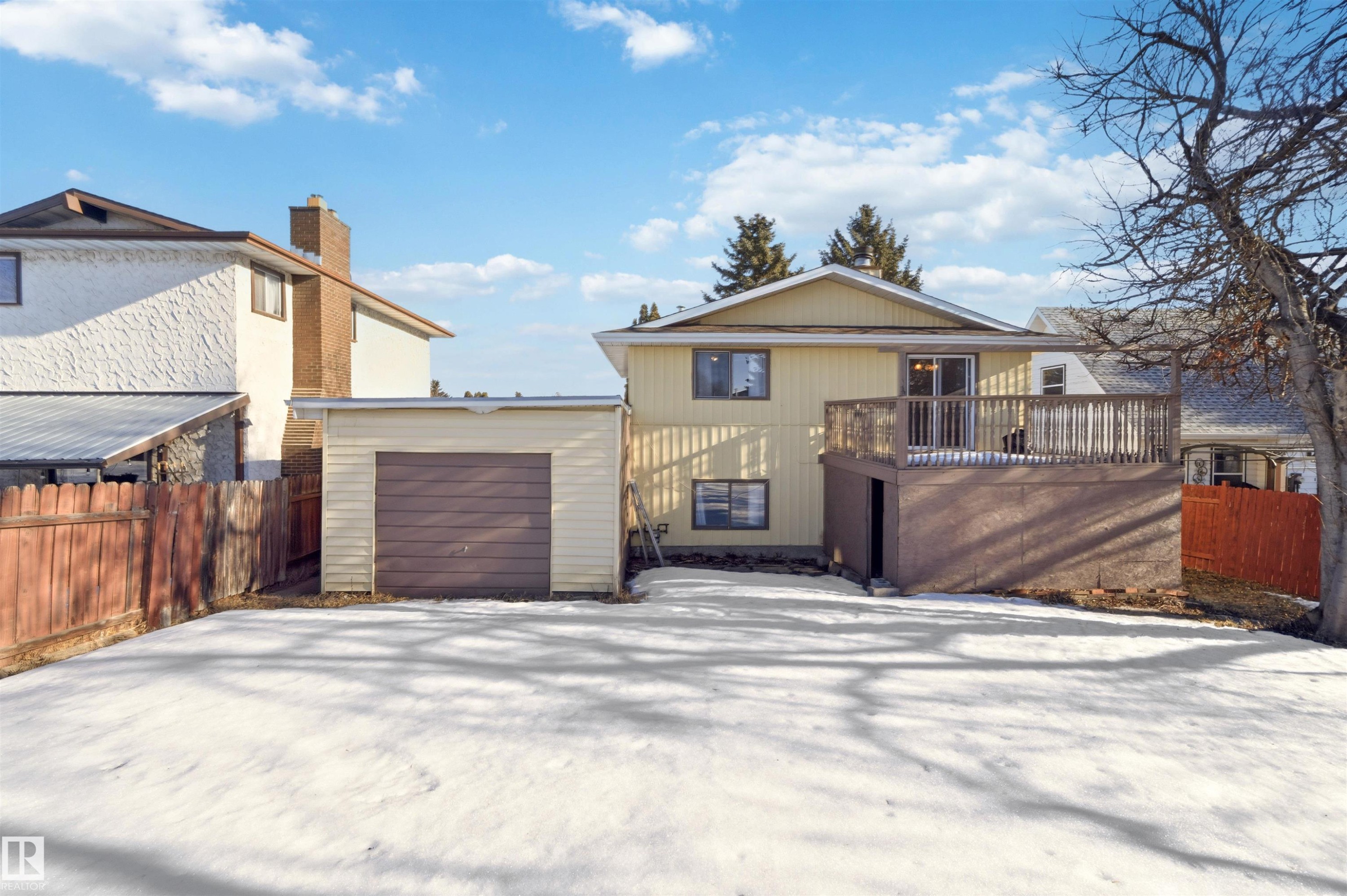 Back of property featuring a chimney, a wooden deck, and a garage - 135 Humberstone Road, Edmonton, AB - Outdoor