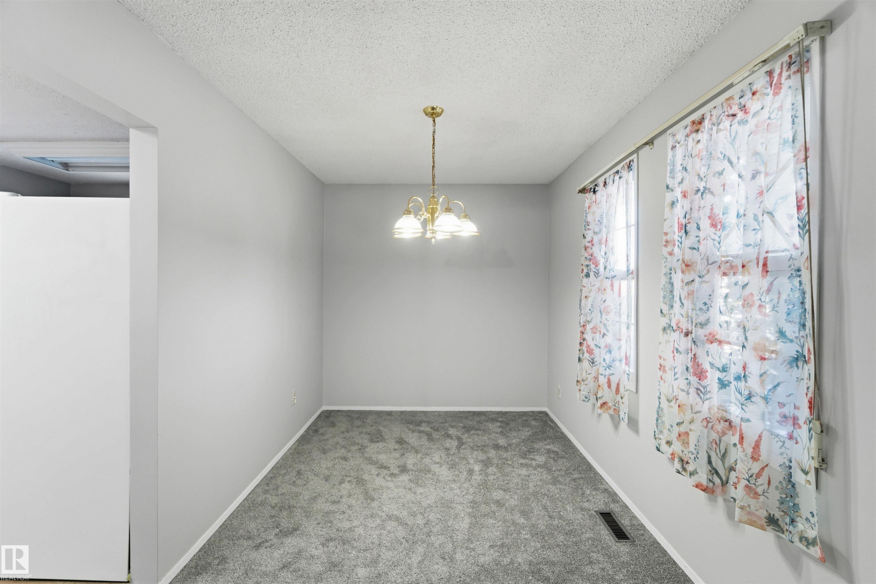 Unfurnished room with light carpet, a chandelier, and a textured ceiling - 135 Humberstone Road, Edmonton, AB - Indoor Photo Showing Other Room