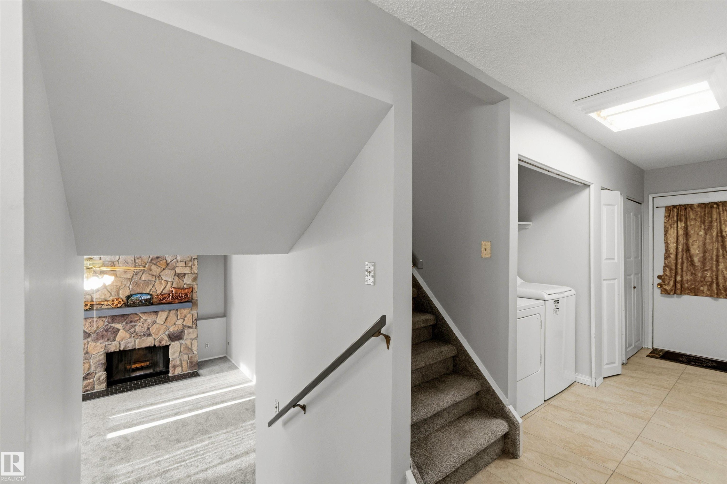 Stairway with a fireplace and washing machine and dryer - 135 Humberstone Road, Edmonton, AB - Indoor Photo Showing Other Room