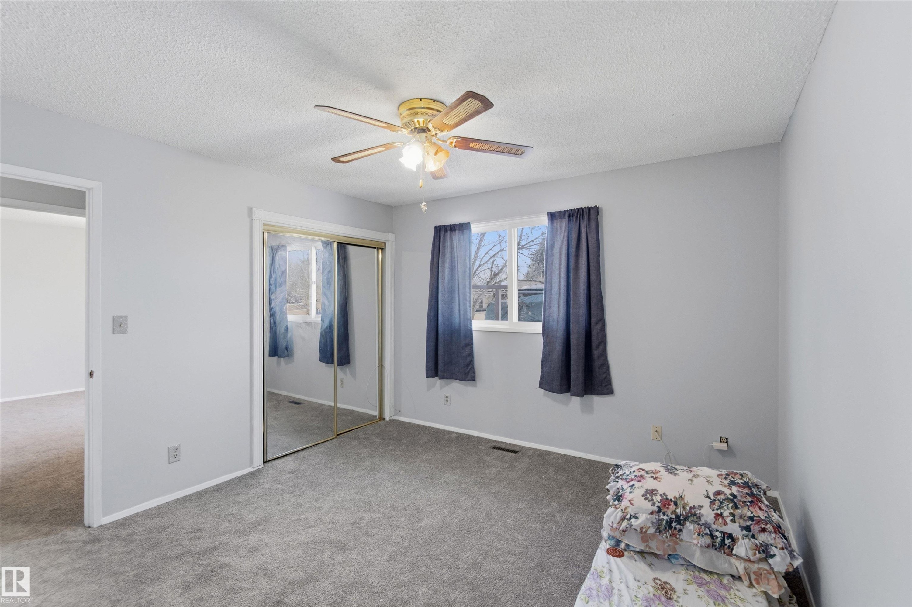 Carpeted bedroom with a ceiling fan, a textured ceiling, and a closet - 135 Humberstone Road, Edmonton, AB - Indoor