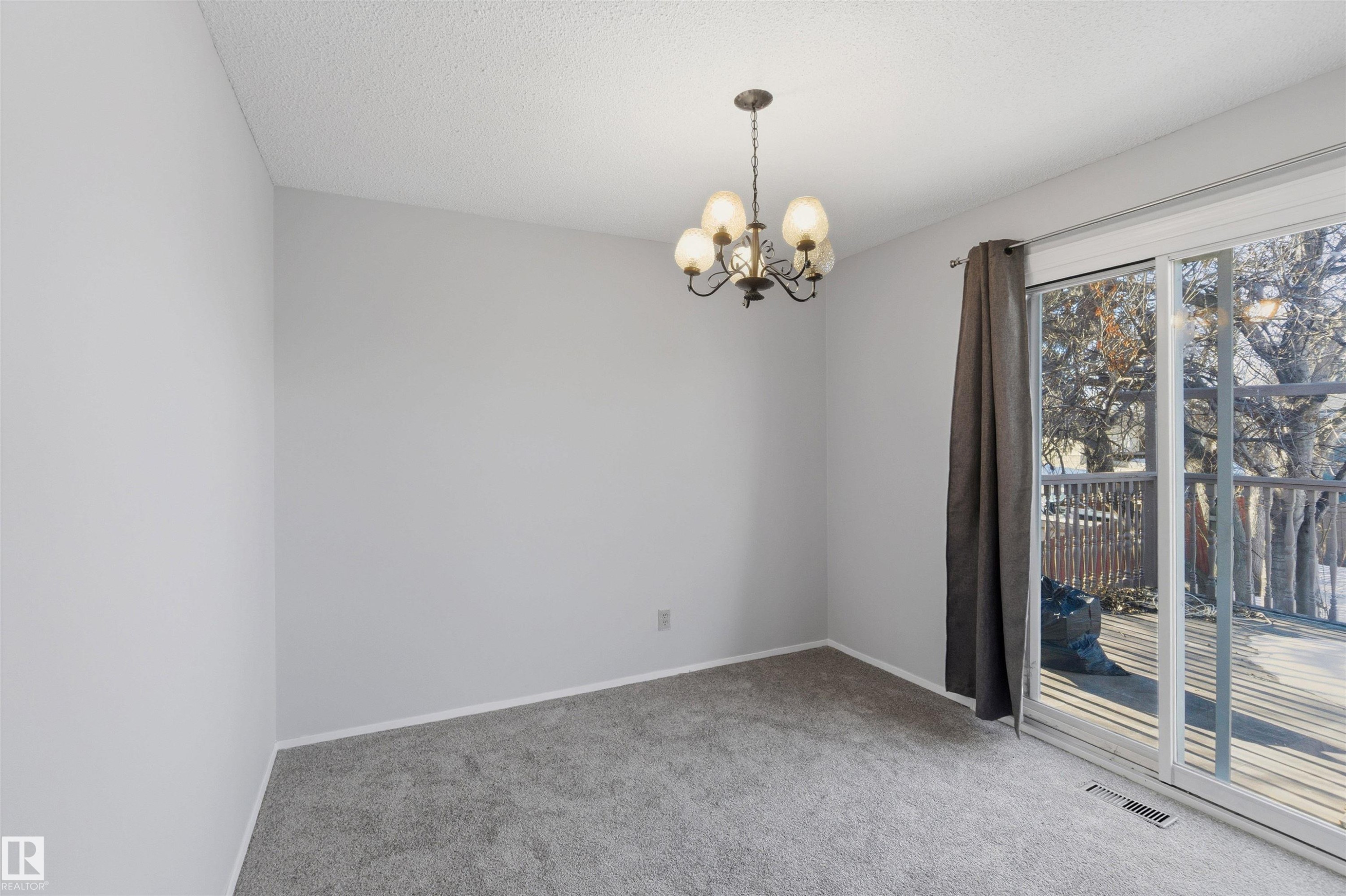 Carpeted spare room with hanging lights and a textured ceiling - 135 Humberstone Road, Edmonton, AB - Indoor Photo Showing Other Room