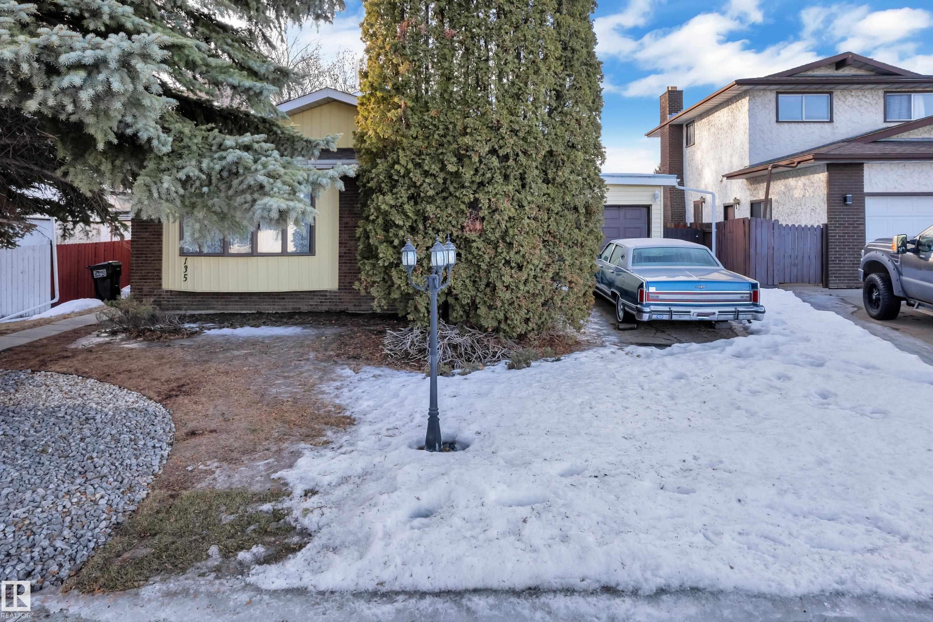 View of front of house with brick siding and a garage - 135 Humberstone Road, Edmonton, AB - Outdoor