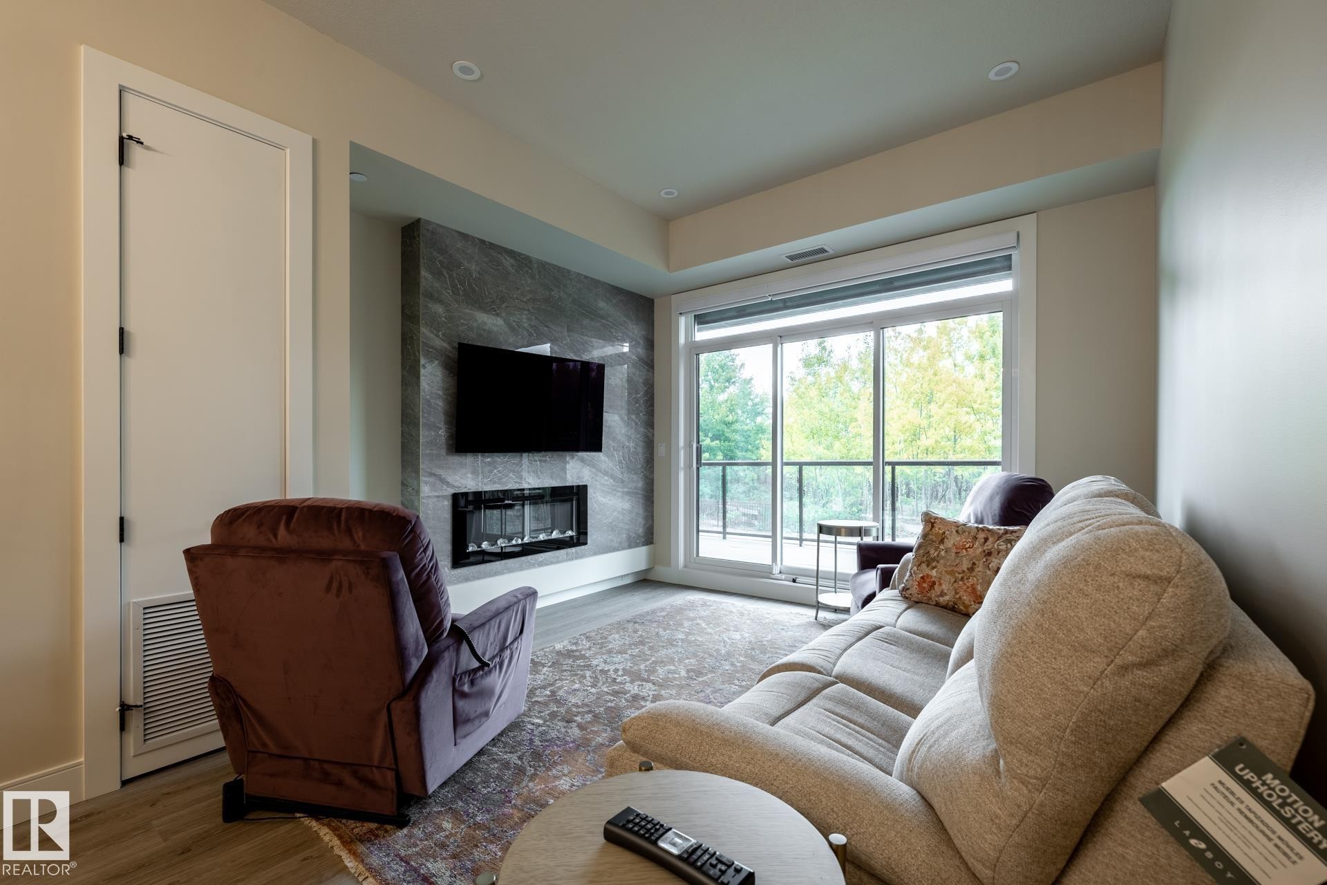 Living area featuring wood finished floors and a premium fireplace - 112 7471 May Common, Edmonton, AB - Indoor Photo Showing Living Room With Fireplace