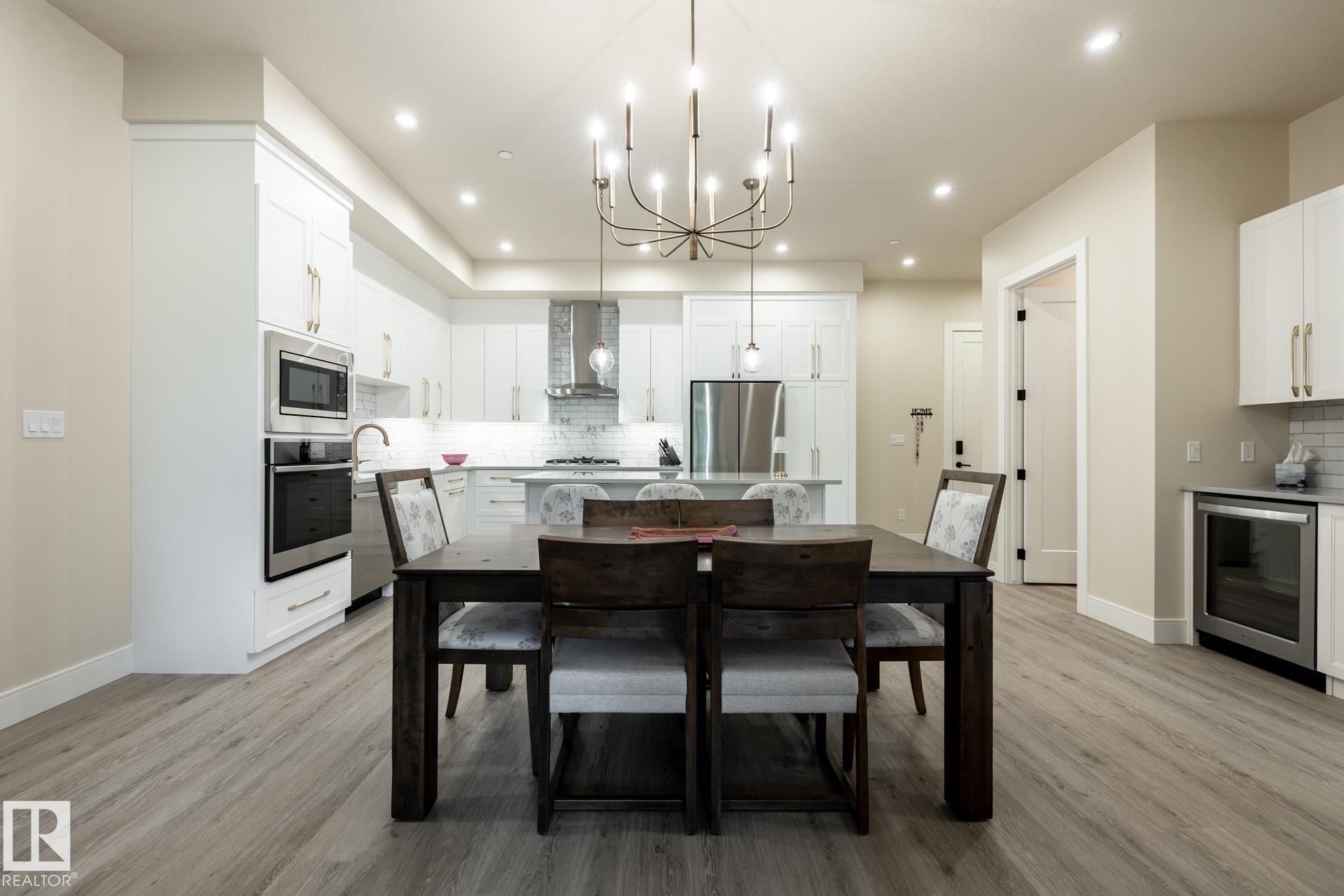 Dining room featuring a chandelier, light wood-type flooring, wine cooler, and recessed lighting - 112 7471 May Common, Edmonton, AB - Indoor