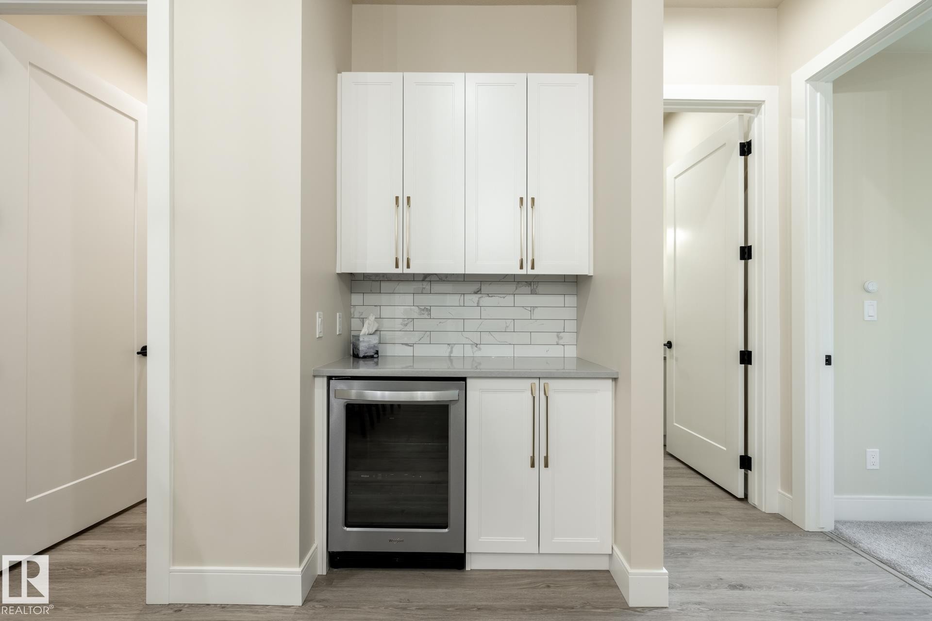 Indoor dry bar featuring wine cooler, white cabinetry, and tasteful backsplash - 112 7471 May Common, Edmonton, AB - Indoor Photo Showing Other Room