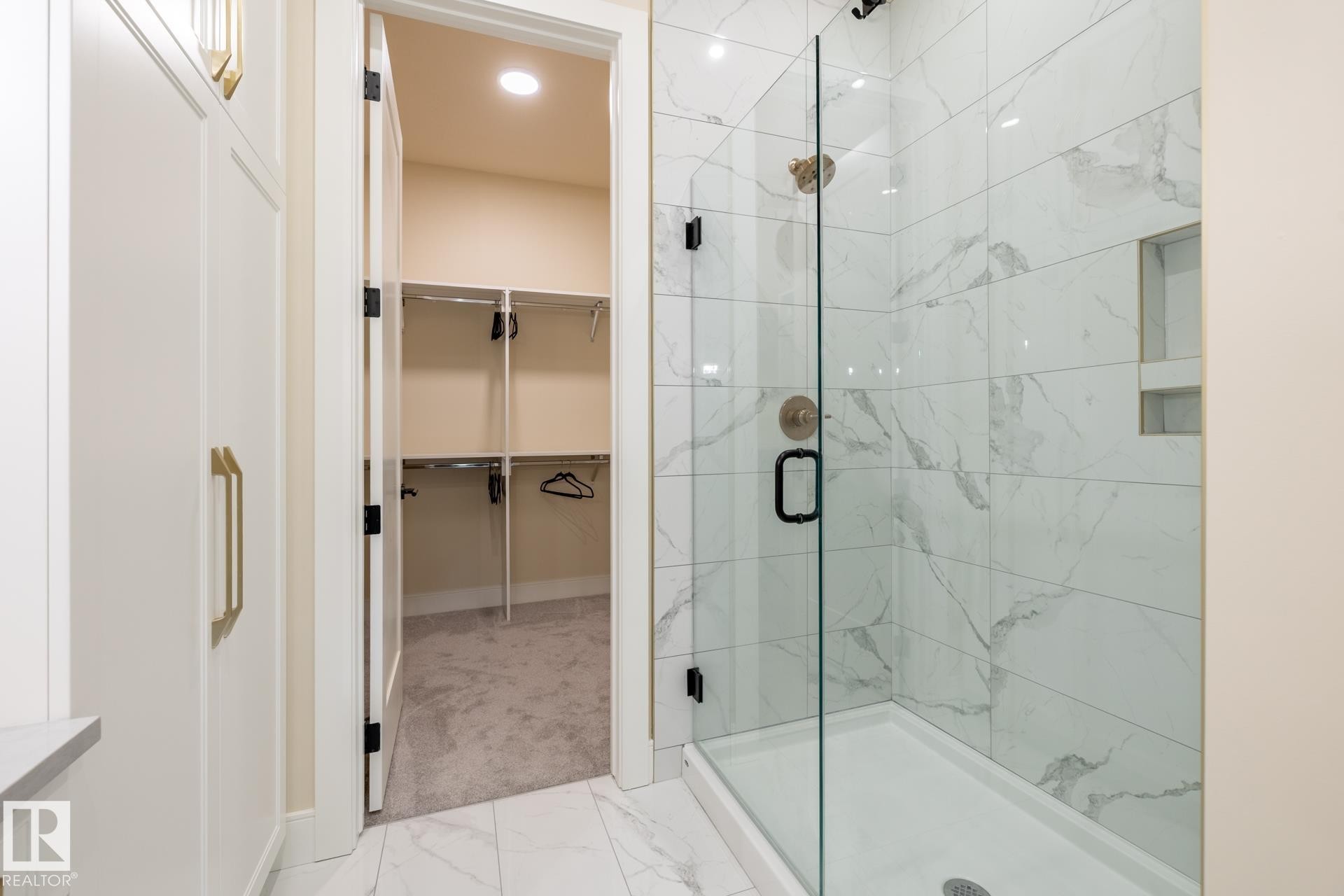 Bathroom featuring a stall shower, light marble finish floors, and a spacious closet - 112 7471 May Common, Edmonton, AB - Indoor Photo Showing Bathroom