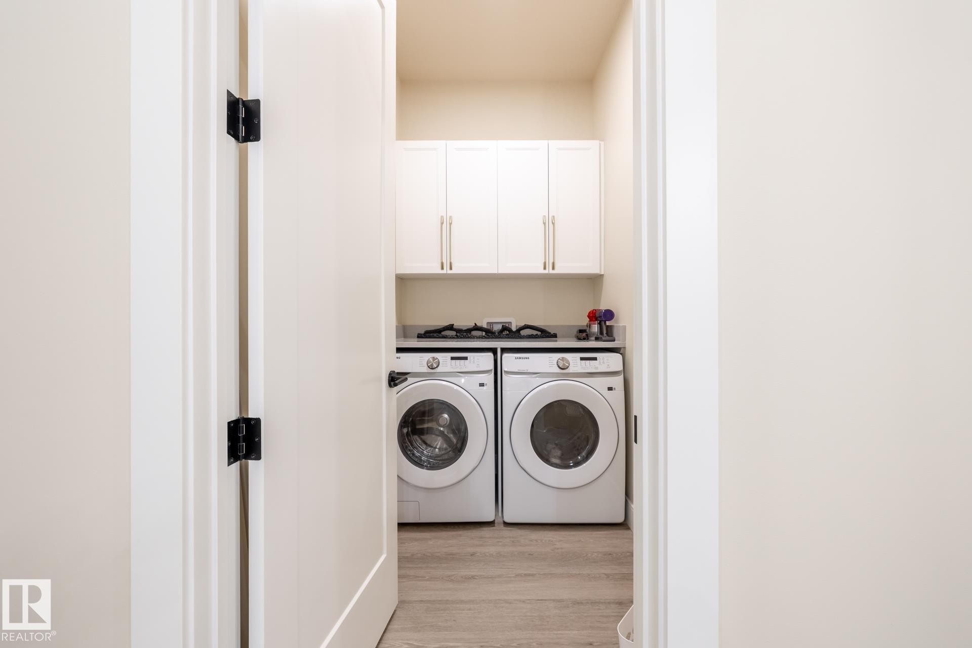 Laundry area with light wood finished floors, separate washer and dryer, and cabinet space - 112 7471 May Common, Edmonton, AB - Indoor Photo Showing Laundry Room