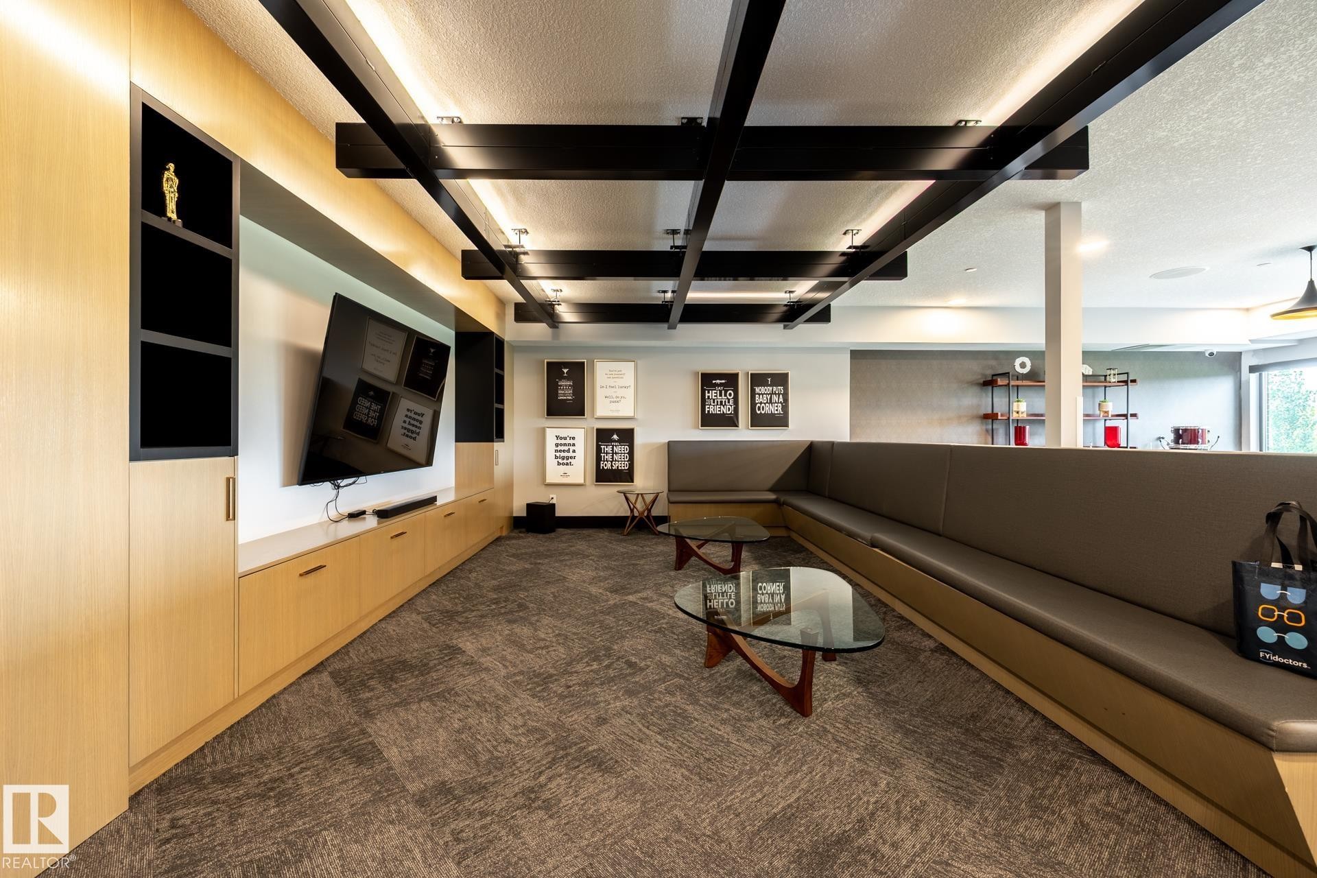 Living area featuring a textured ceiling, dark carpet, and beam ceiling - 112 7471 May Common, Edmonton, AB - Indoor Photo Showing Other Room