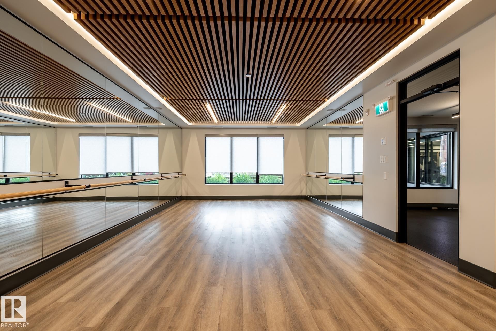 Exercise area with baseboards and wood finished floors - 112 7471 May Common, Edmonton, AB - Indoor Photo Showing Other Room