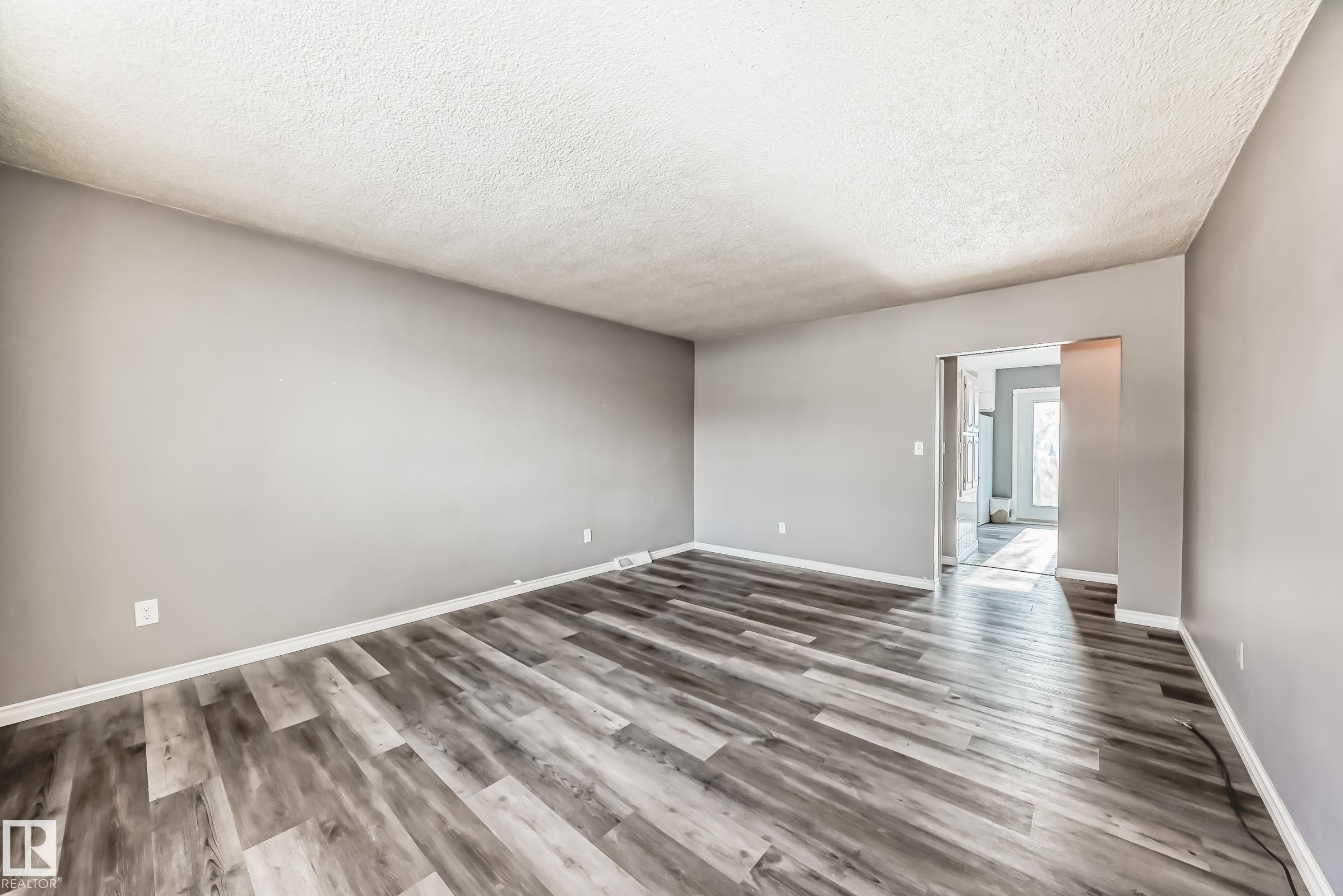 Empty room featuring wood finished floors and a textured ceiling - 8639 64 Avenue Nw, Edmonton, AB - Indoor Photo Showing Other Room