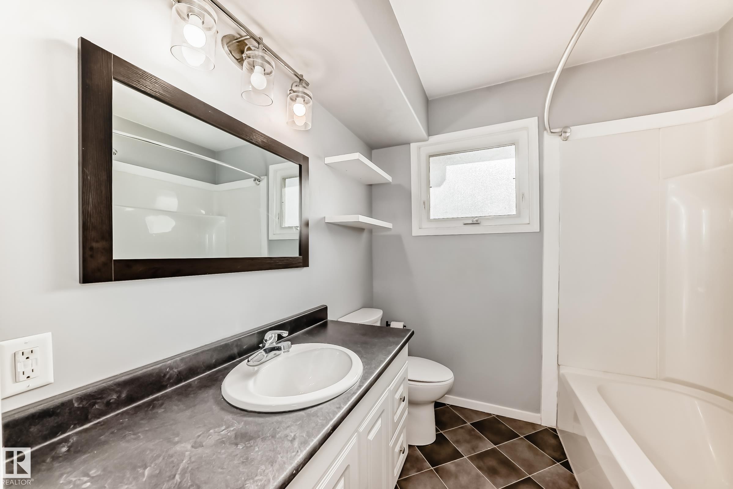 Bathroom with vanity, shower / washtub combination, and dark tile patterned flooring - 8639 64 Avenue Nw, Edmonton, AB - Indoor Photo Showing Bathroom