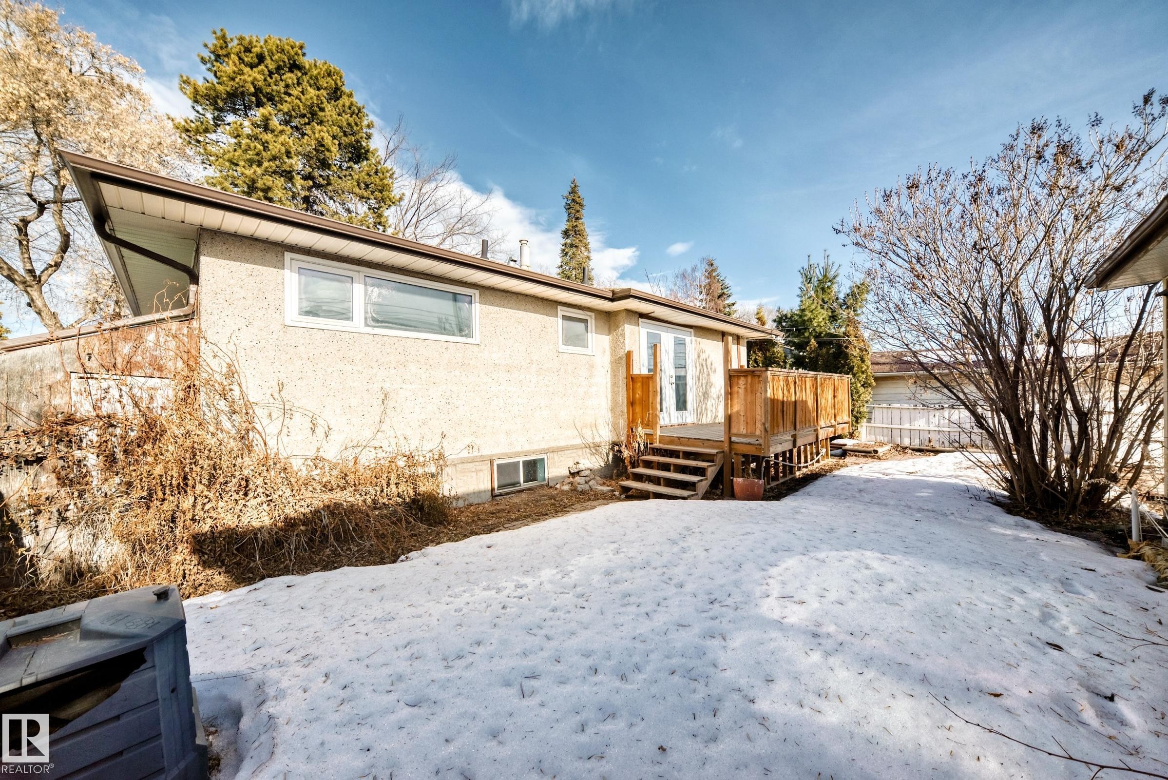 Snow covered house featuring stucco siding and a wooden deck - 8639 64 Avenue Nw, Edmonton, AB - Outdoor