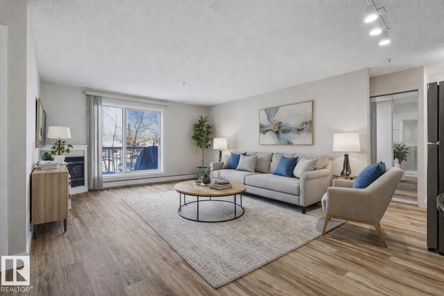 The living room features hardwood style flooring, a large window with a view of trees, and recessed lighting - 237 17447 98A Avenue, Edmonton, AB - Indoor Photo Showing Living Room