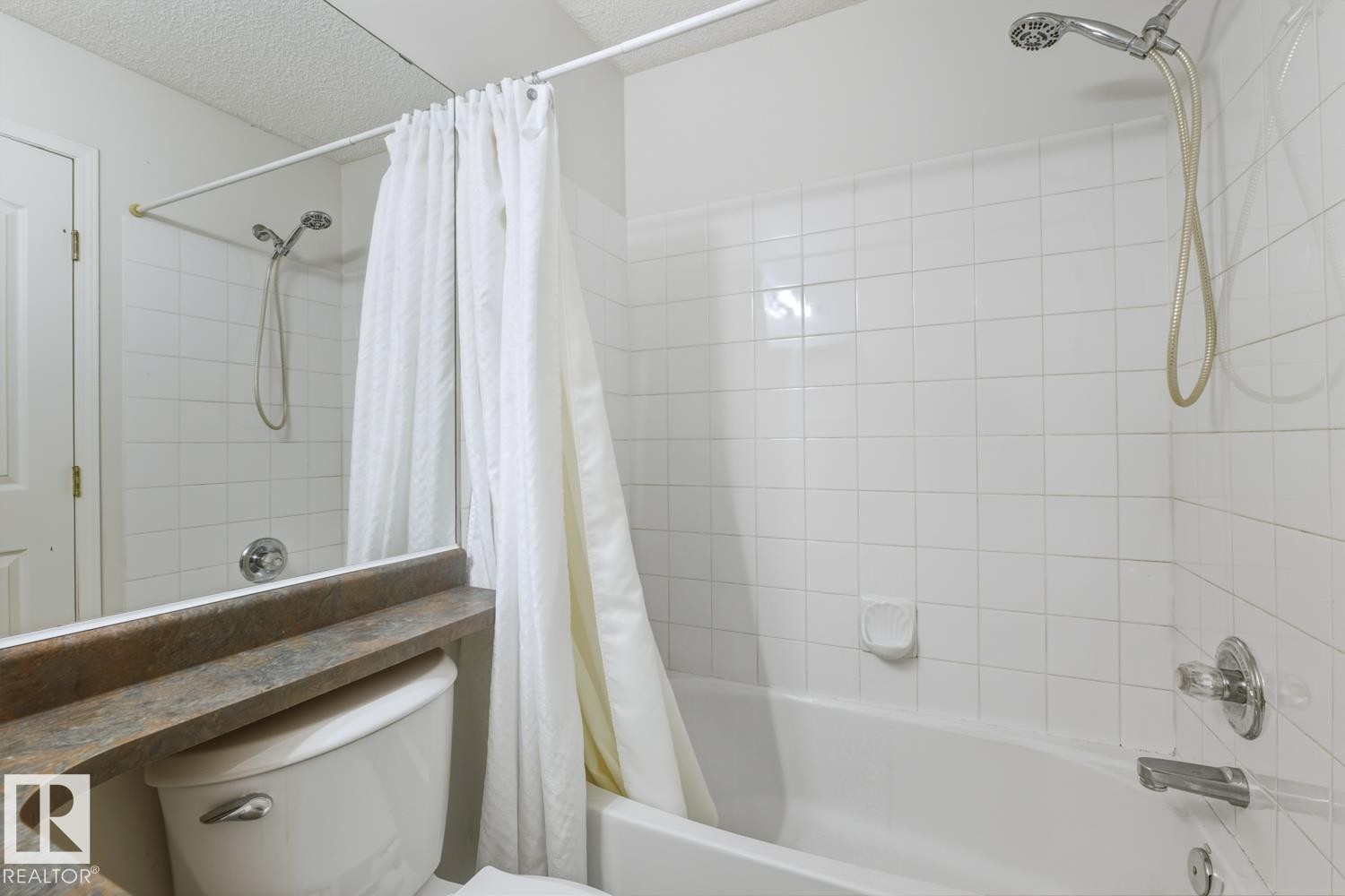 Bathroom featuring a tiled shower and tub combination, a toilet, and a vanity countertop - 237 17447 98A Avenue, Edmonton, AB - Indoor Photo Showing Bathroom