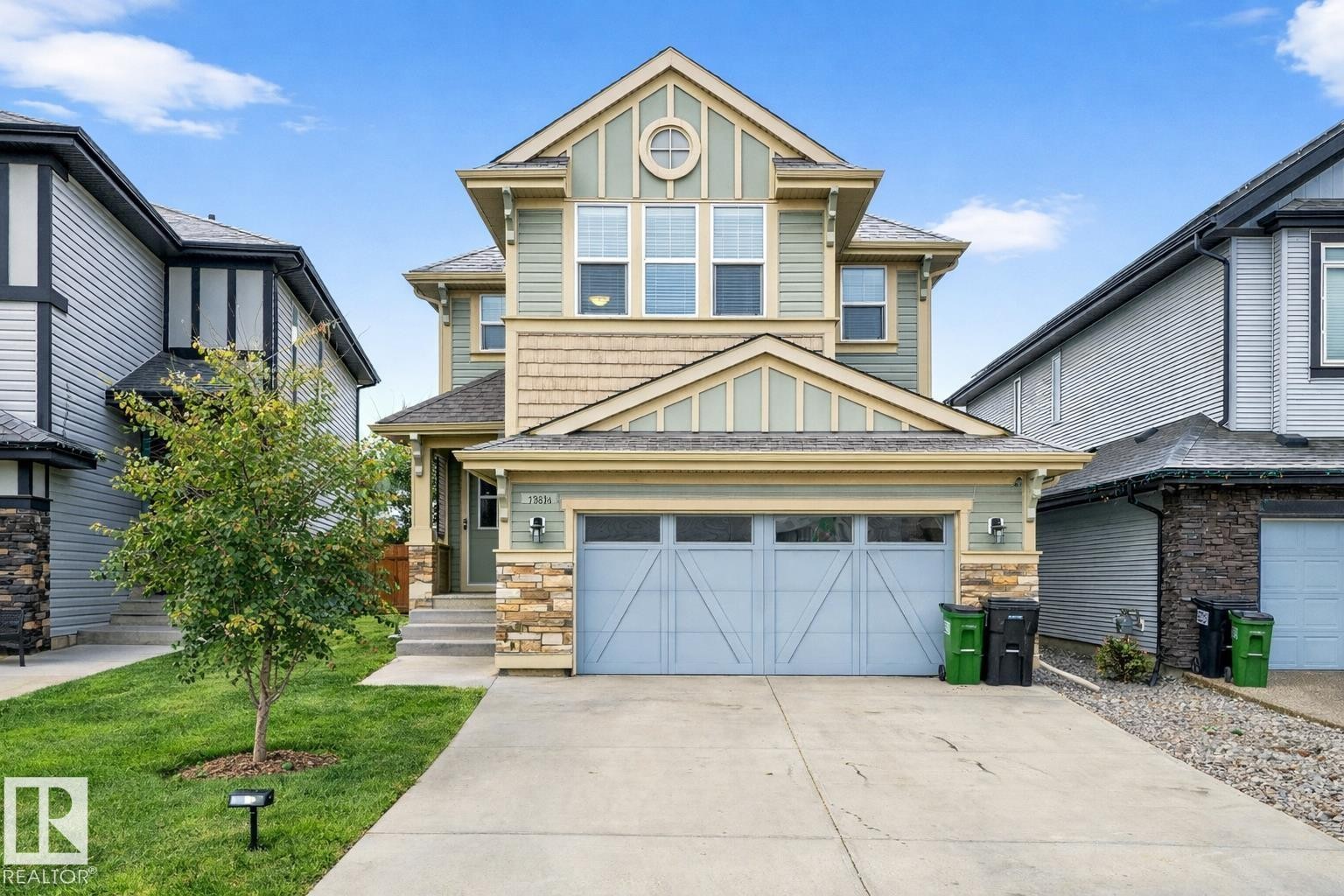 A charming exterior featuring light green siding, beige shingles, and stone accents - 17838 60A Street, Edmonton, AB - Outdoor With Facade