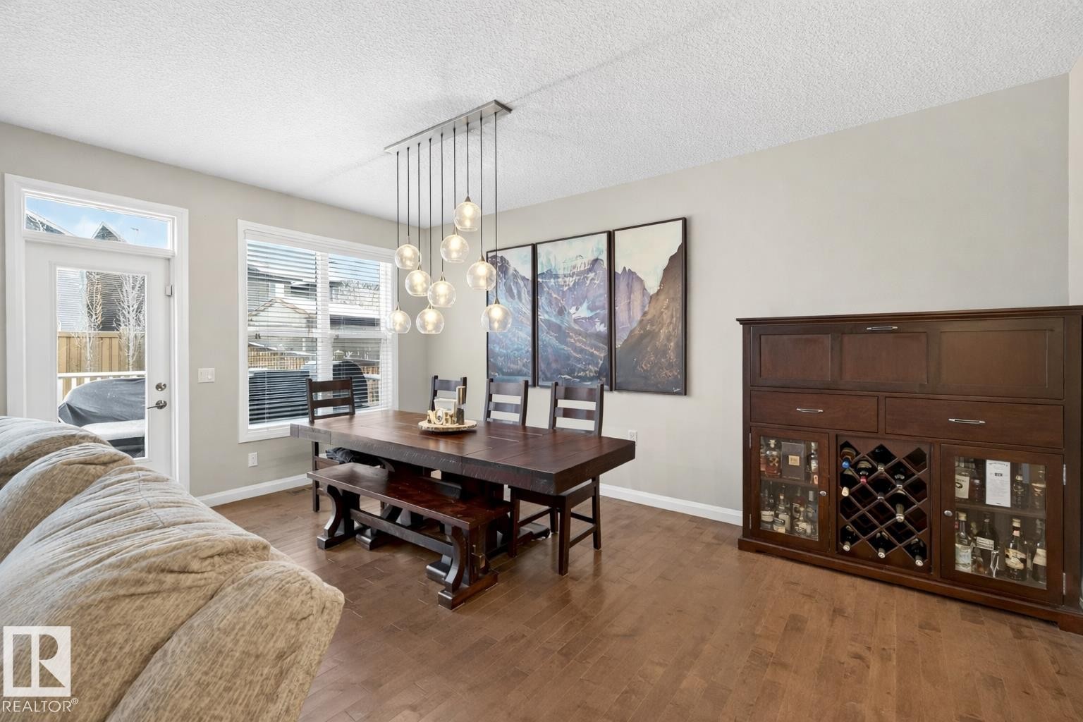 The dining area features hardwood floors and a contemporary chandelier with globe lighting - 17838 60A Street, Edmonton, AB - Indoor