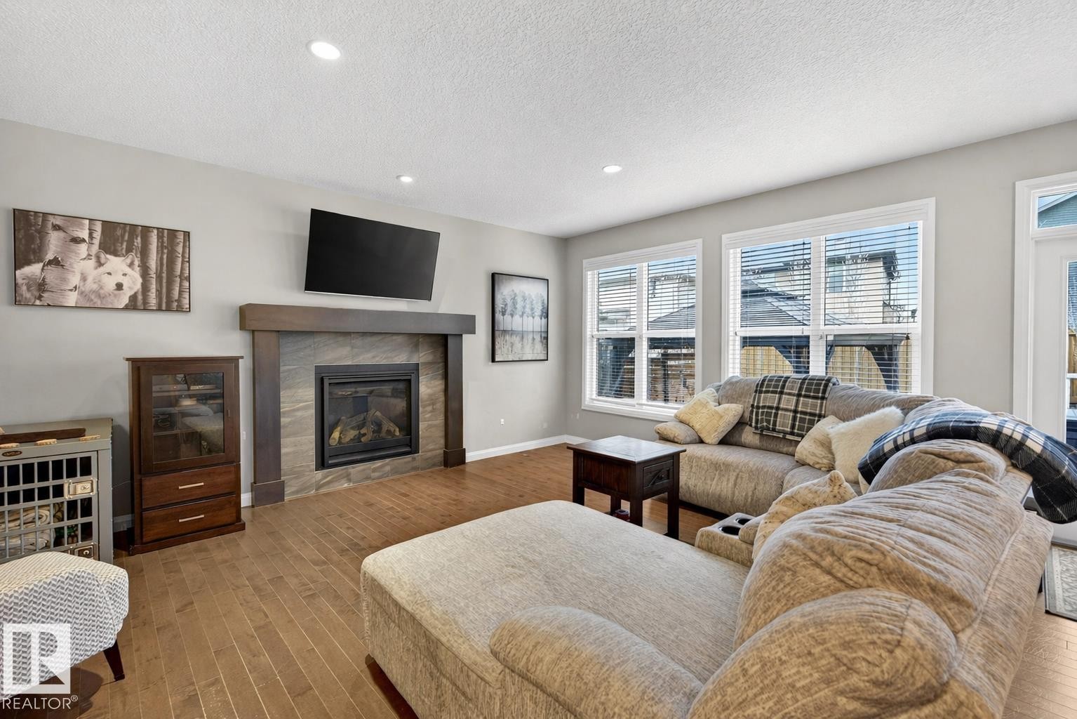 The living room features hardwood flooring, recessed lighting, and a fireplace with a stone surround and a wooden mantel - 17838 60A Street, Edmonton, AB - Indoor Photo Showing Living Room With Fireplace