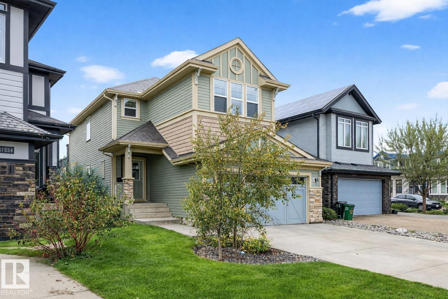 The property features a well-maintained lawn, a concrete driveway, and a two-car garage - 17838 60A Street, Edmonton, AB - Outdoor With Facade