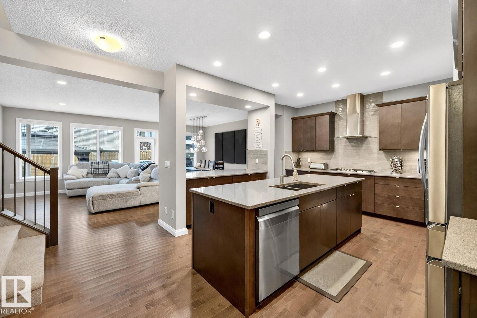The property features a kitchen with dark wood cabinetry, stainless steel appliances, and an island with a sink and countertop space - 17838 60A Street, Edmonton, AB - Indoor Photo Showing Kitchen With Double Sink With Upgraded Kitchen
