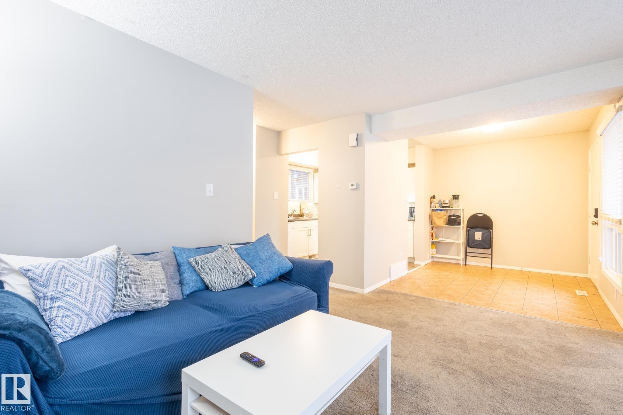Living area with light tile patterned flooring and light colored carpet - 3530 42 Street, Edmonton, AB - Indoor Photo Showing Living Room