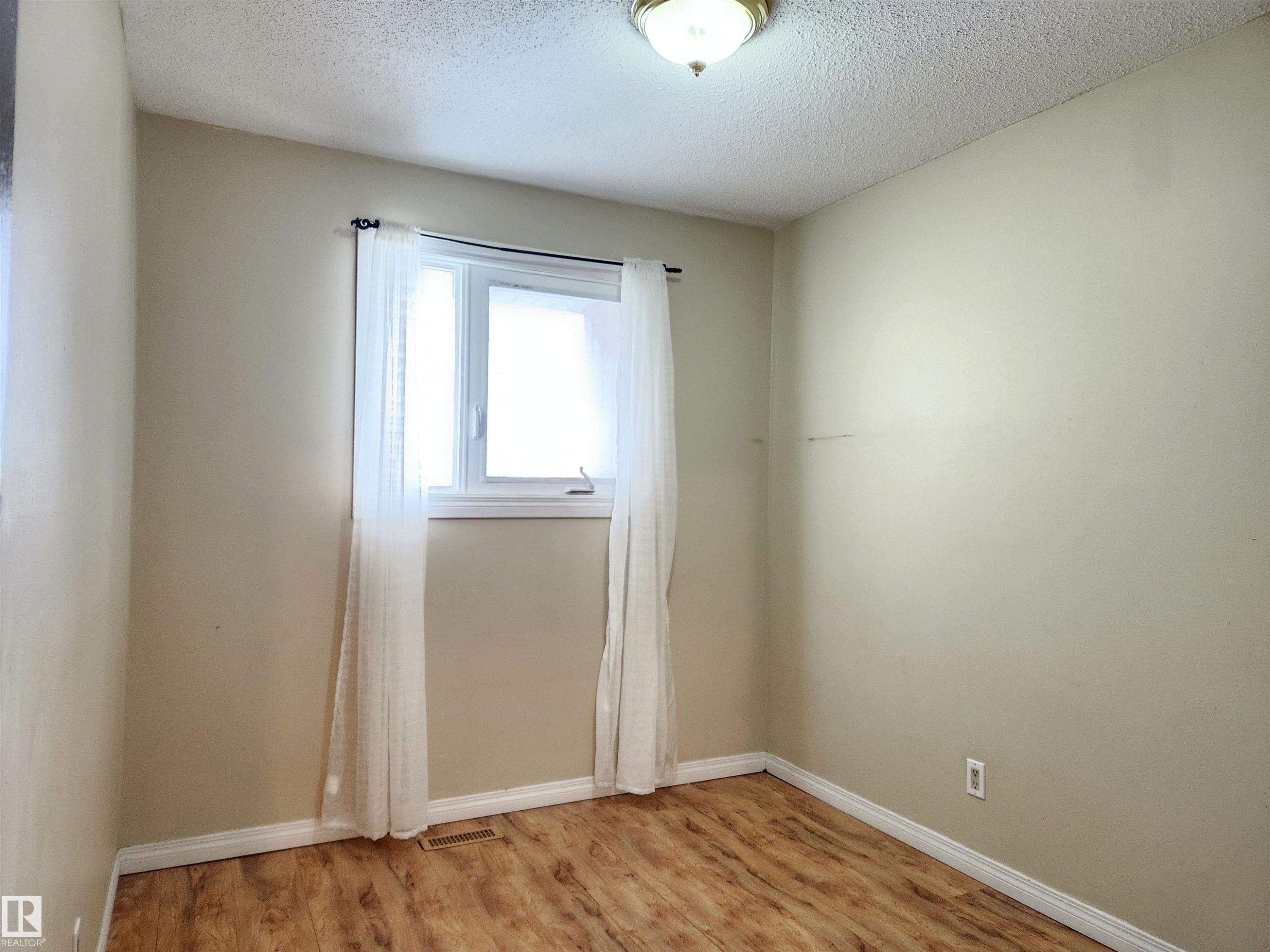 Empty room with light wood-type flooring and a textured ceiling - 6 14320 80 Street, Edmonton, AB - Indoor Photo Showing Other Room