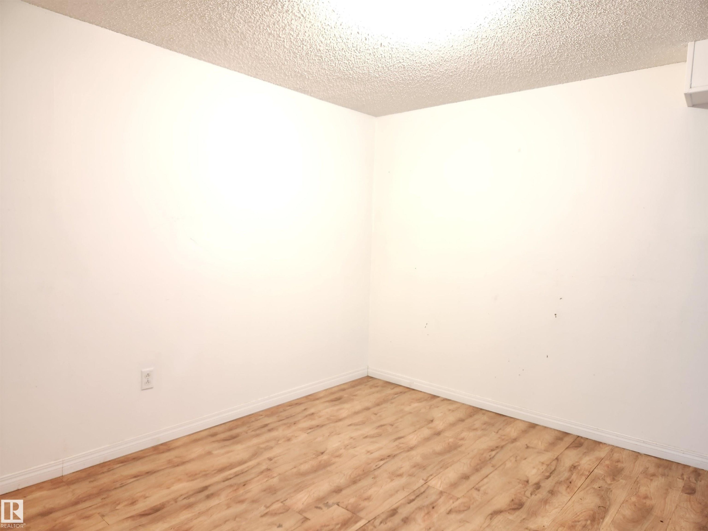 Empty room with wood finished floors and a textured ceiling - 6 14320 80 Street, Edmonton, AB - Indoor Photo Showing Other Room