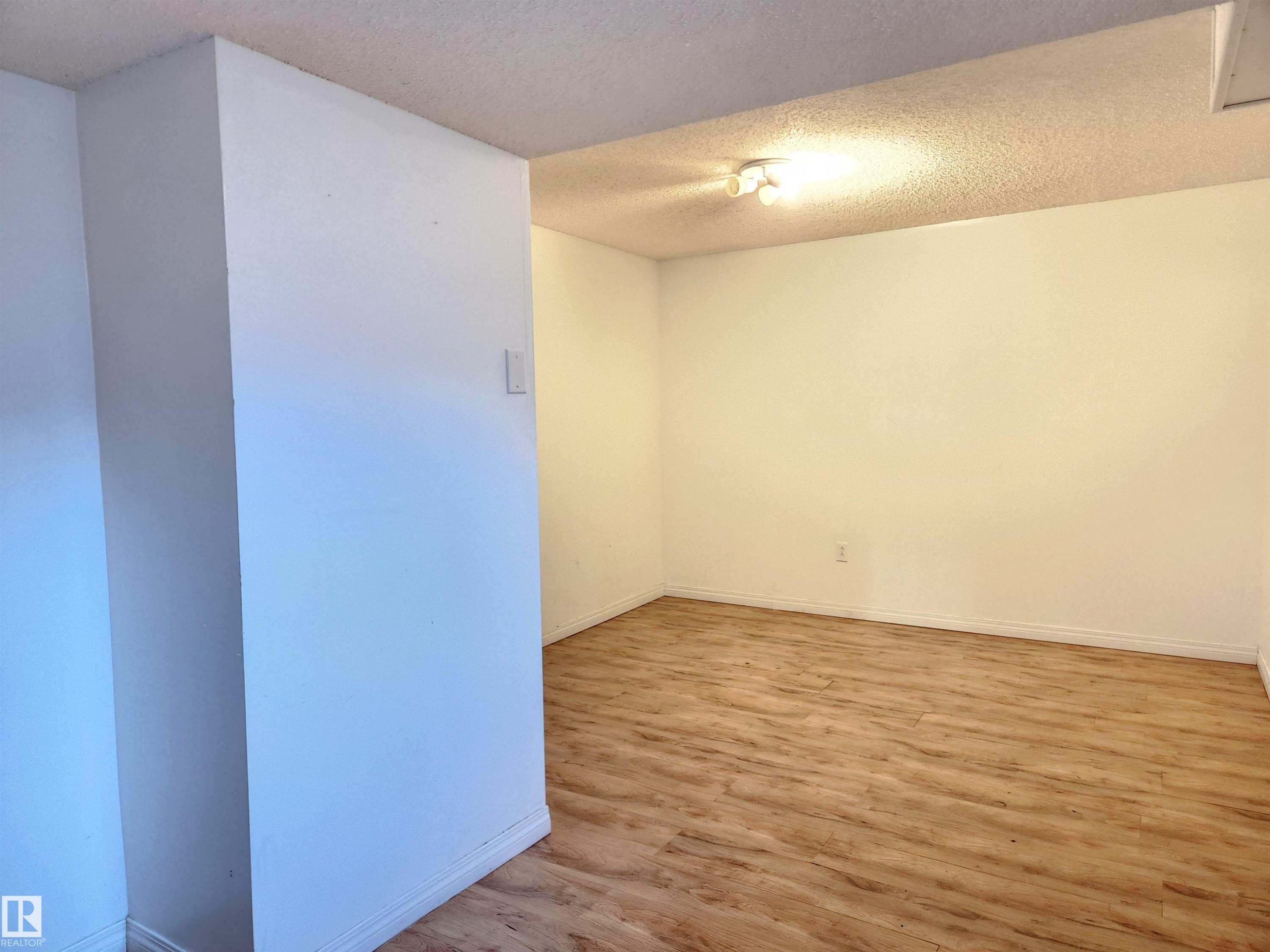 Unfurnished room with a textured ceiling and light wood-style floors - 6 14320 80 Street, Edmonton, AB - Indoor Photo Showing Other Room