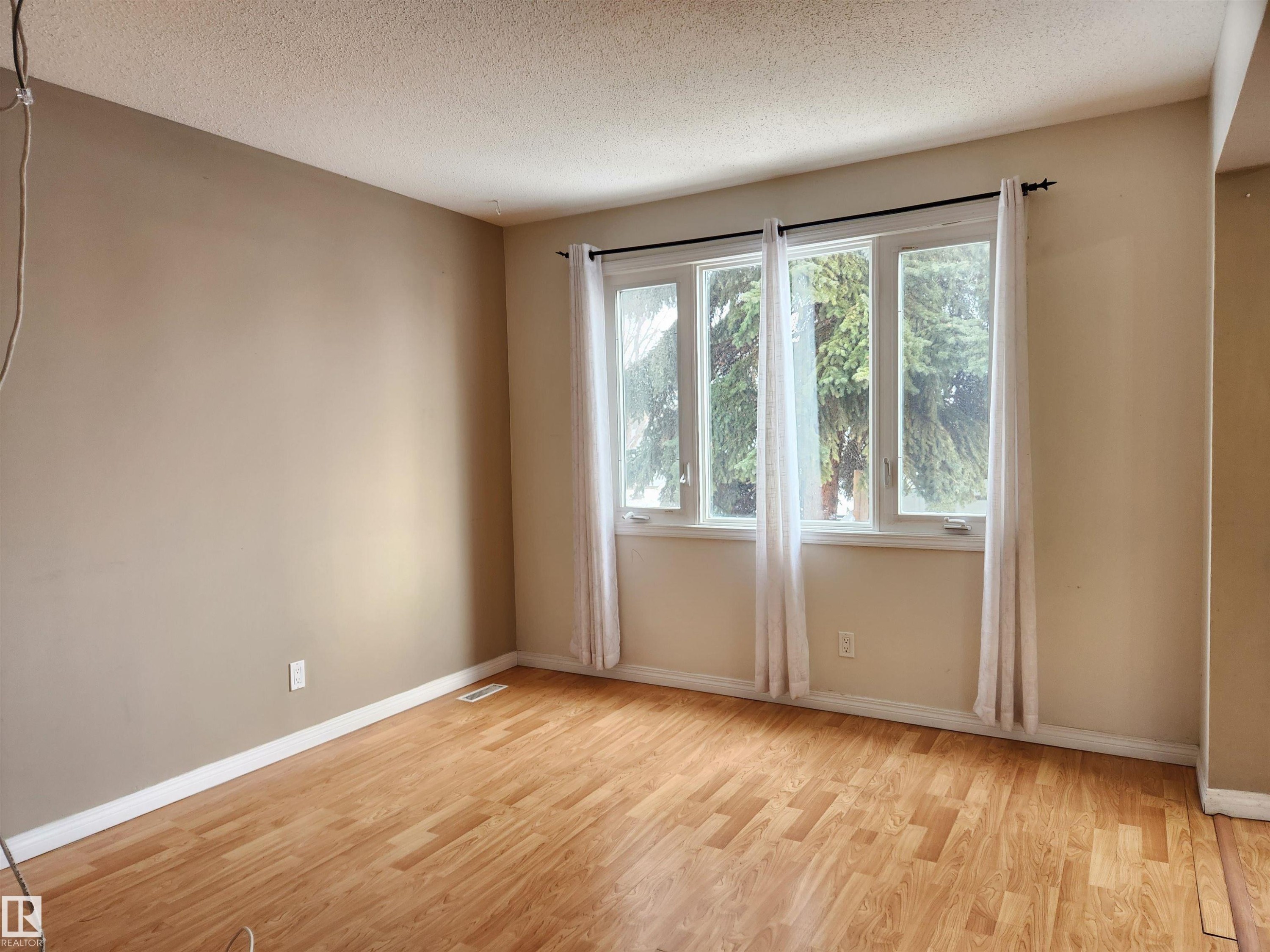 Spare room with light wood-style flooring and a textured ceiling - 6 14320 80 Street, Edmonton, AB - Indoor Photo Showing Other Room