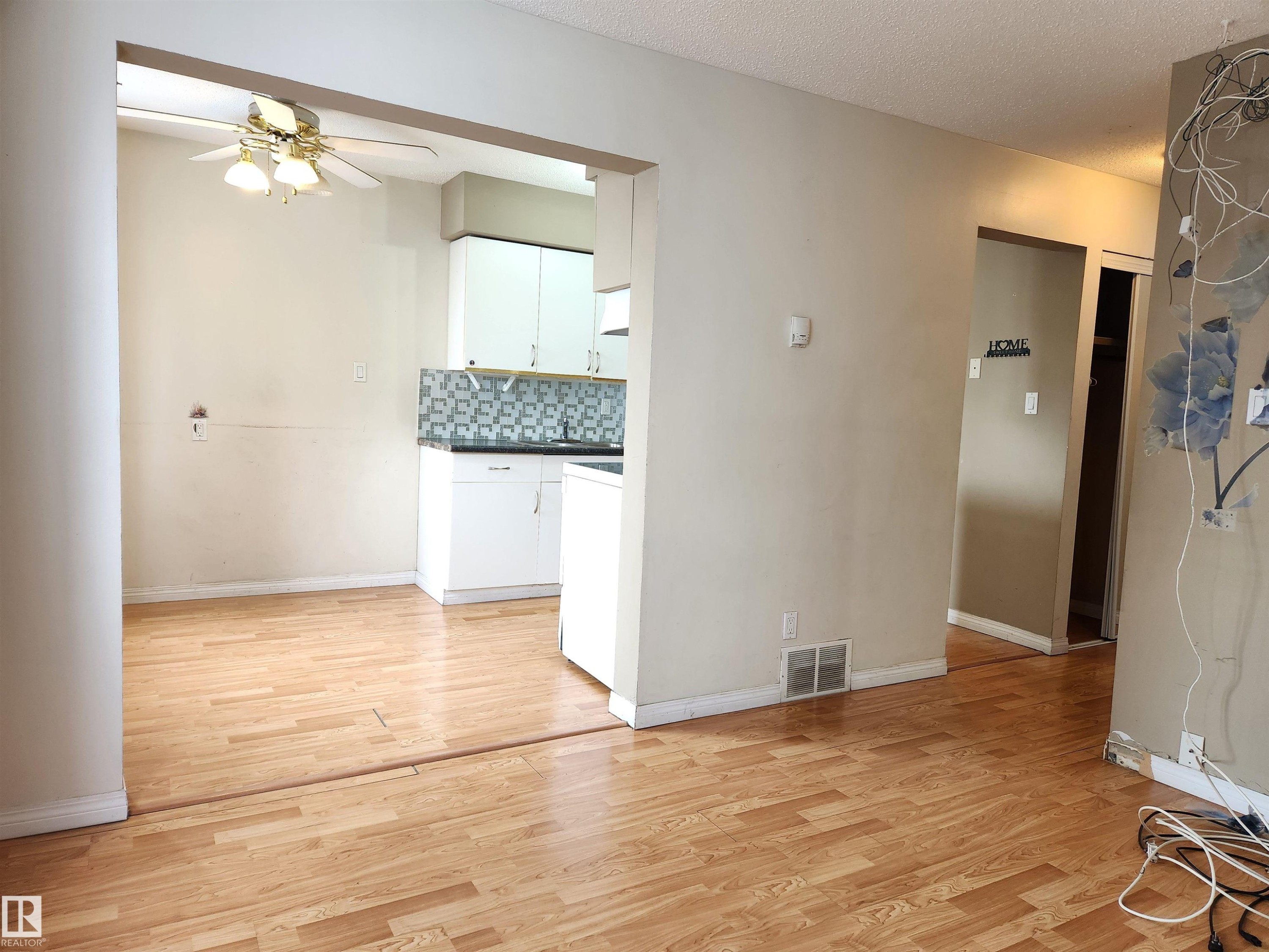 Kitchen featuring dark countertops, white cabinetry, light wood-style floors, ceiling fan, and backsplash - 6 14320 80 Street, Edmonton, AB - Indoor